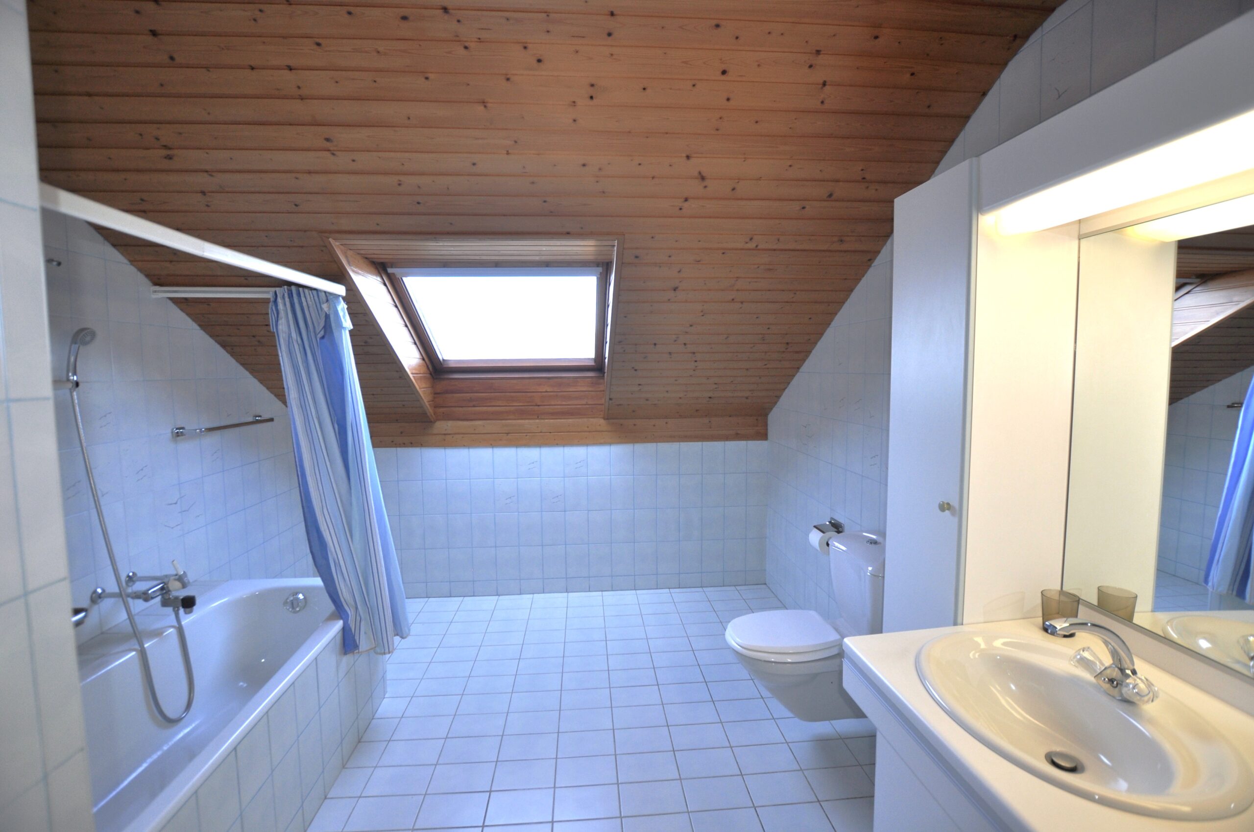 Dachgeschoss-Badezimmer mit Badewanne und Fenster