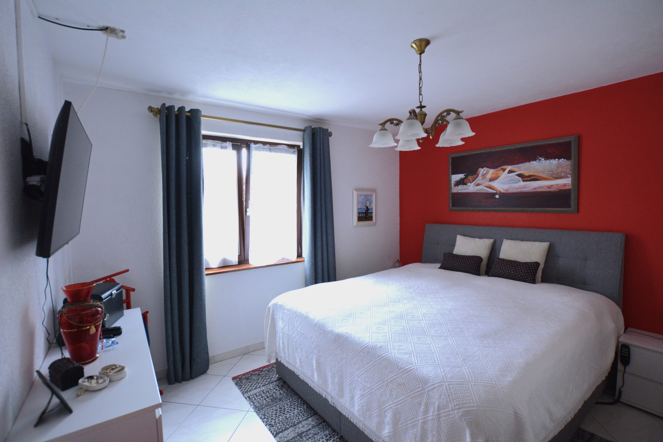 Schlafzimmer mit Doppelbett und roter Akzentwand