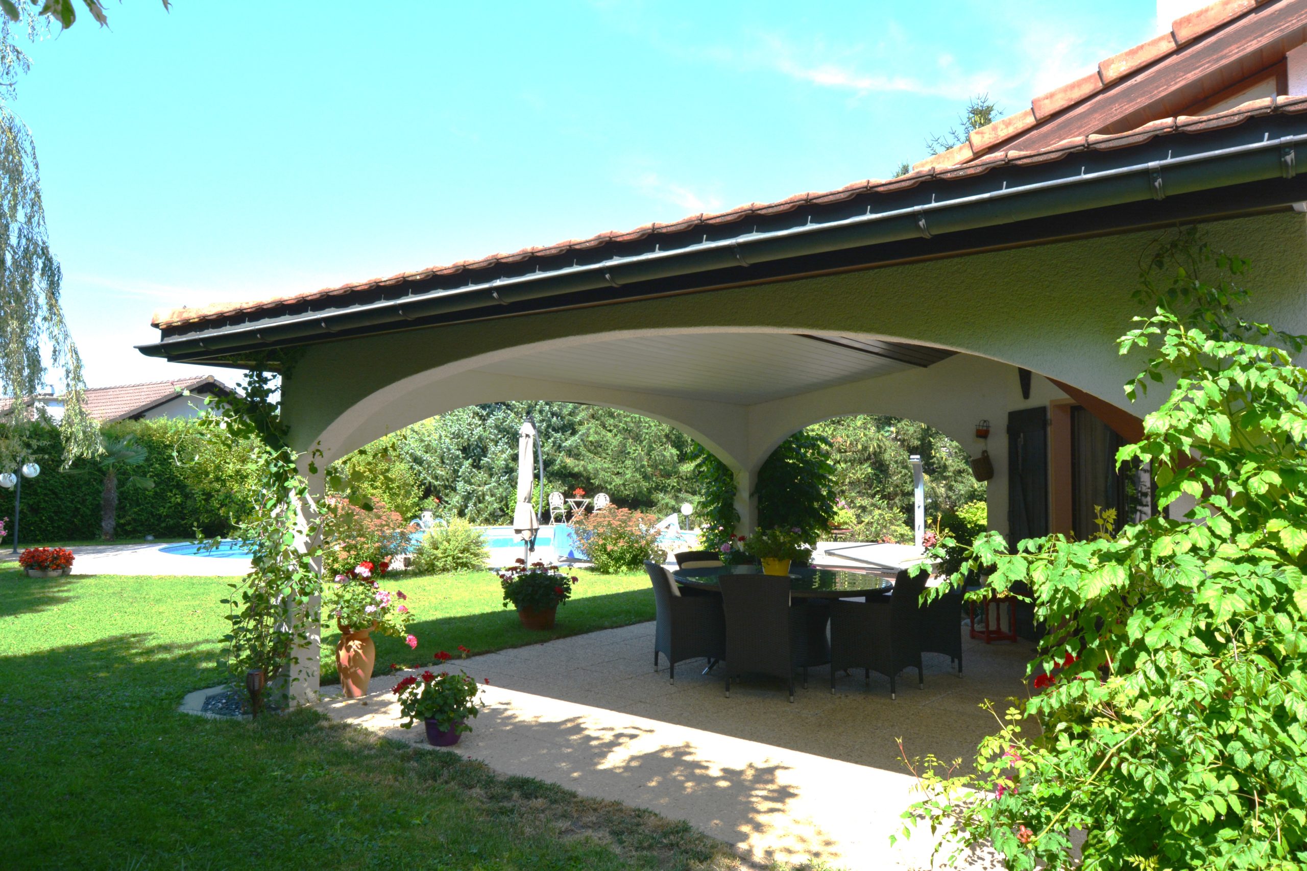 Überdachte Terrasse mit Garten und Poolblick