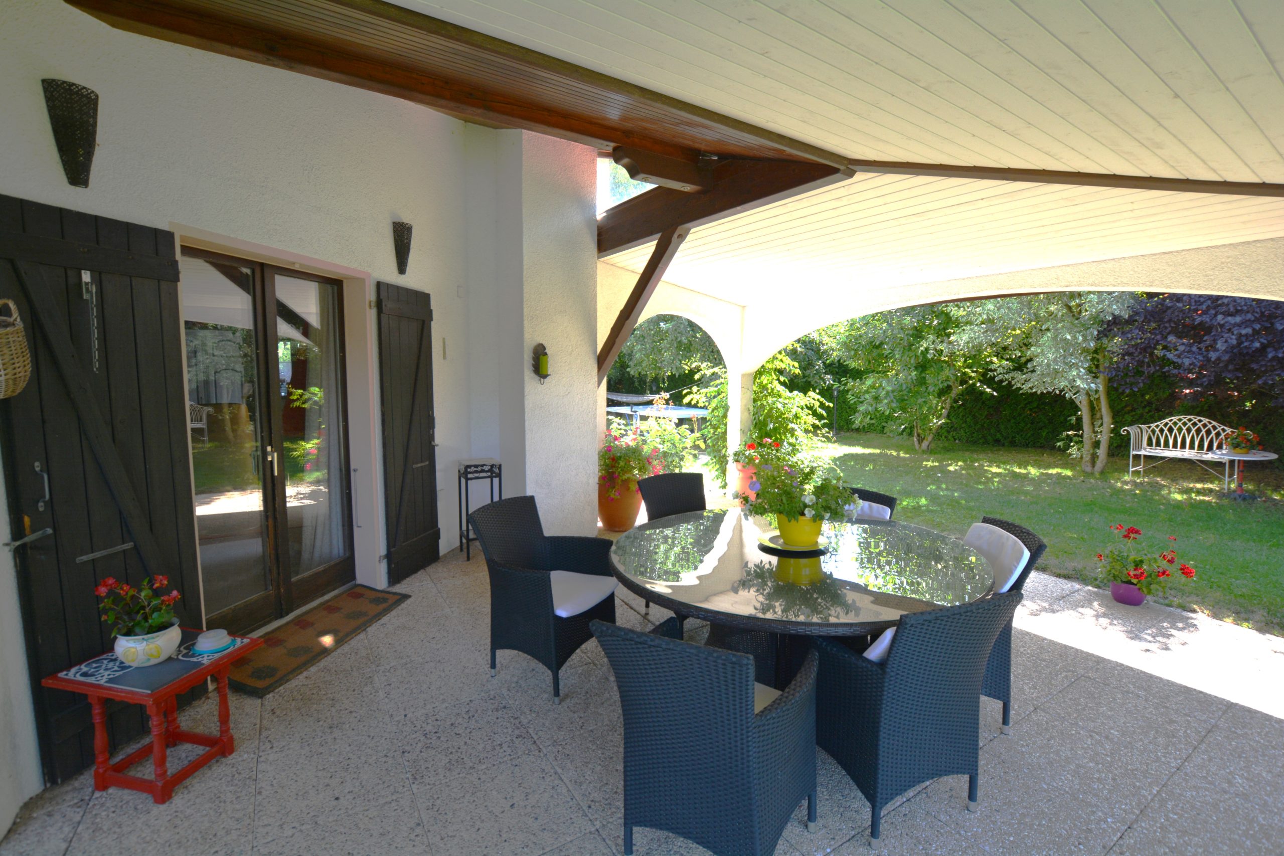 Überdachte Terrasse mit Sitzgruppe und Gartenblick