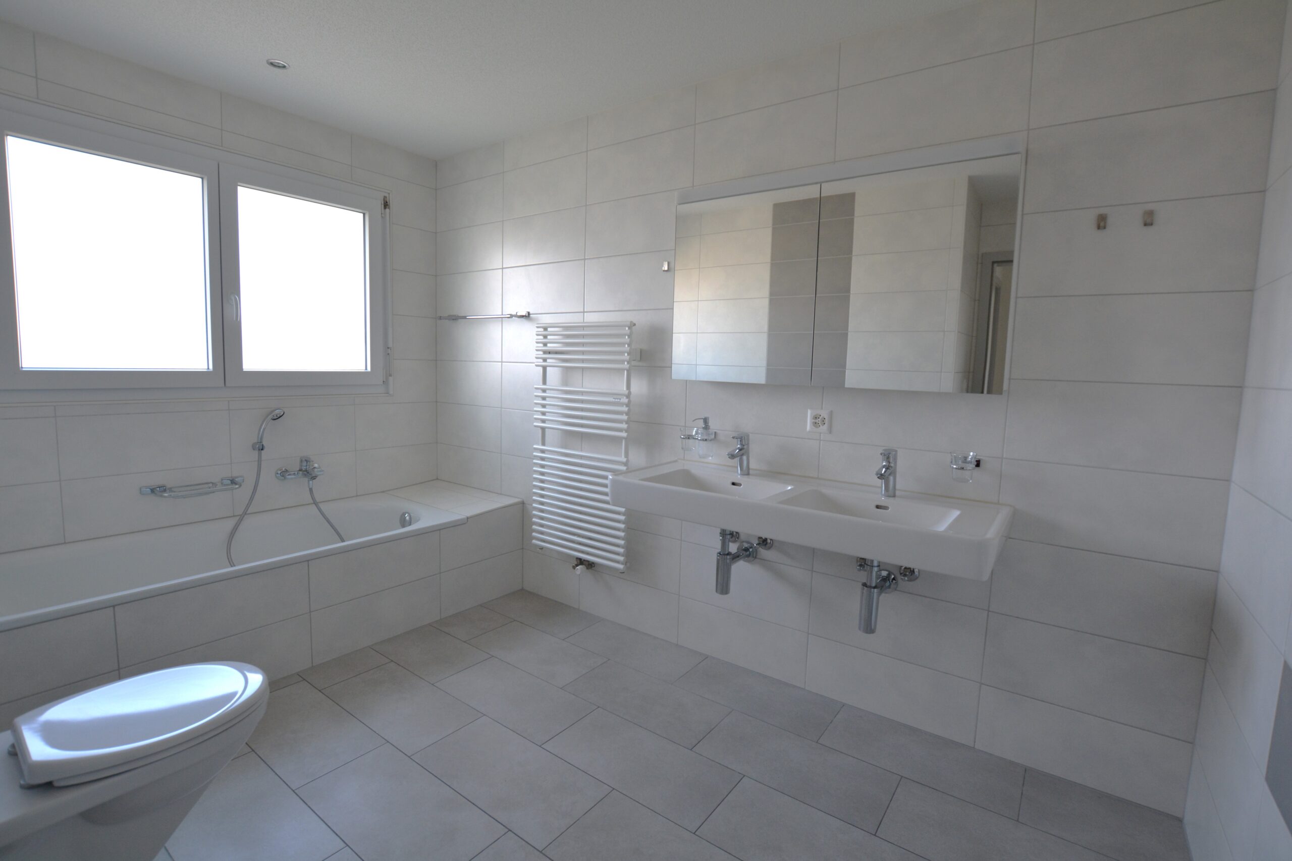 Modernes, helles Badezimmer mit Wanne und Doppelwaschtisch