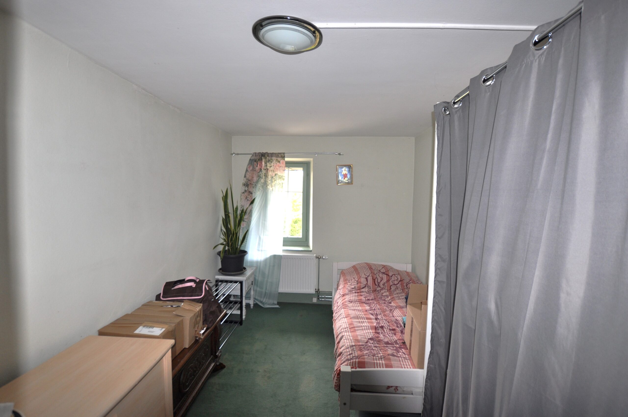 Kompaktes Schlafzimmer mit Bett und Vorhängen