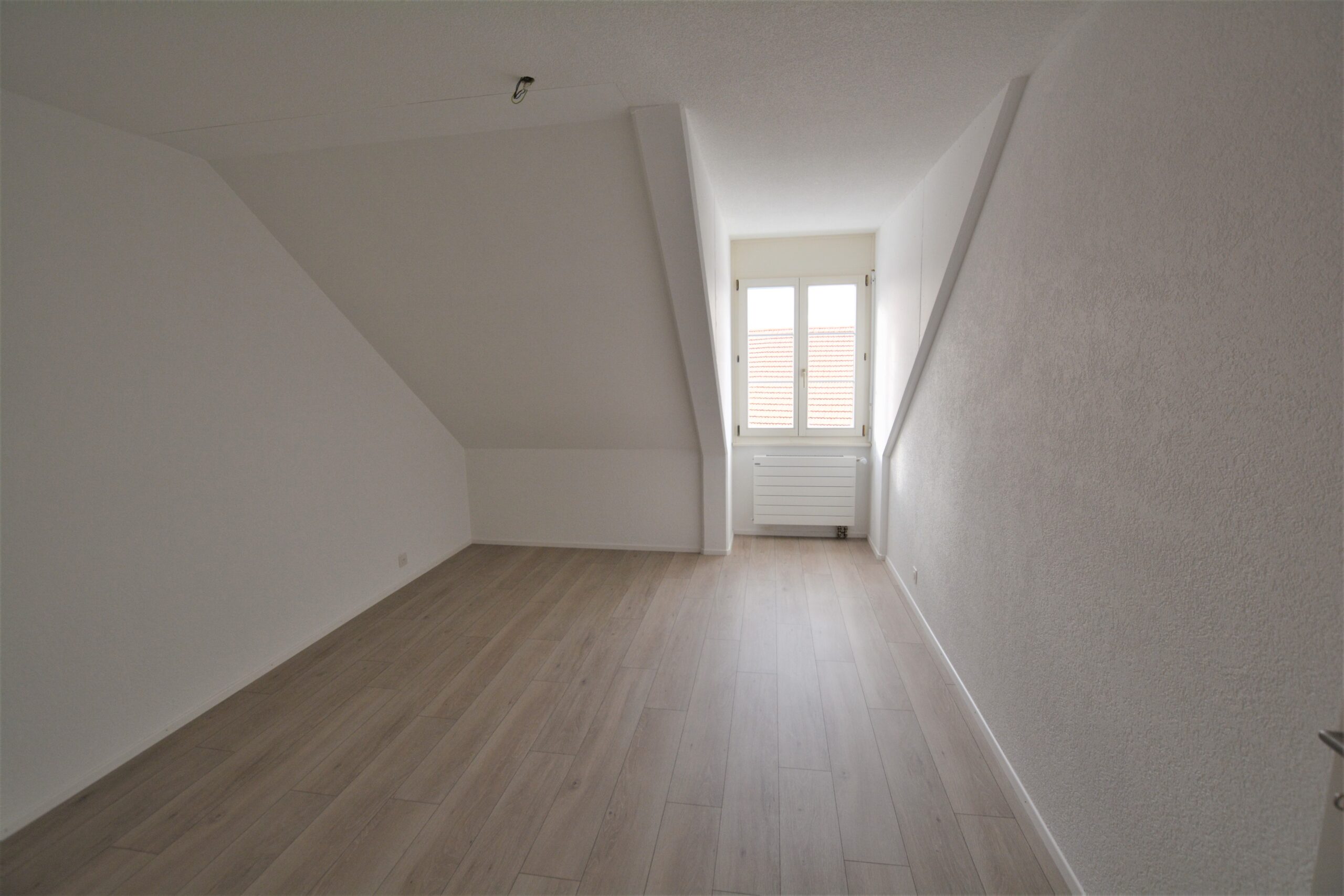 Dachzimmer mit Fenster und Heizkörper