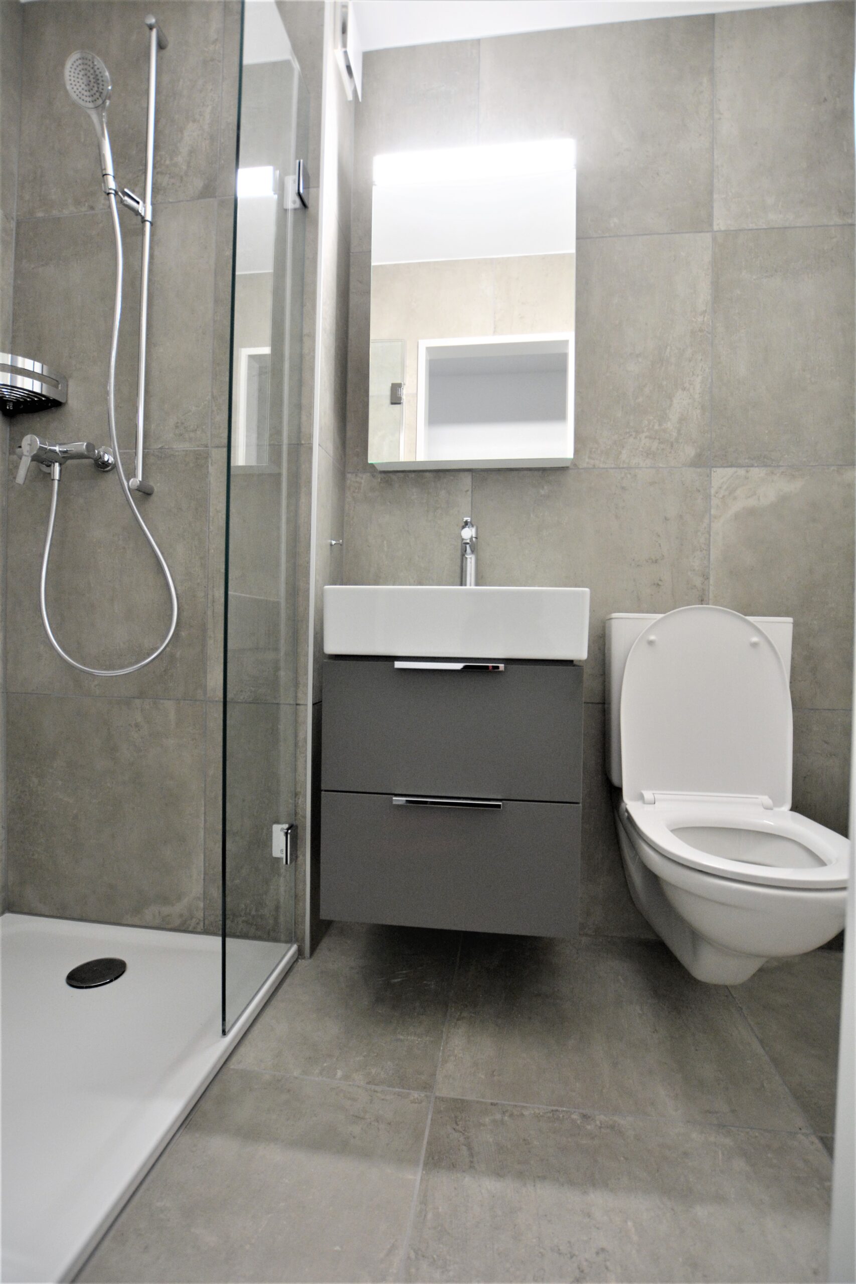 Modernes Badezimmer mit Dusche, Waschtisch und WC