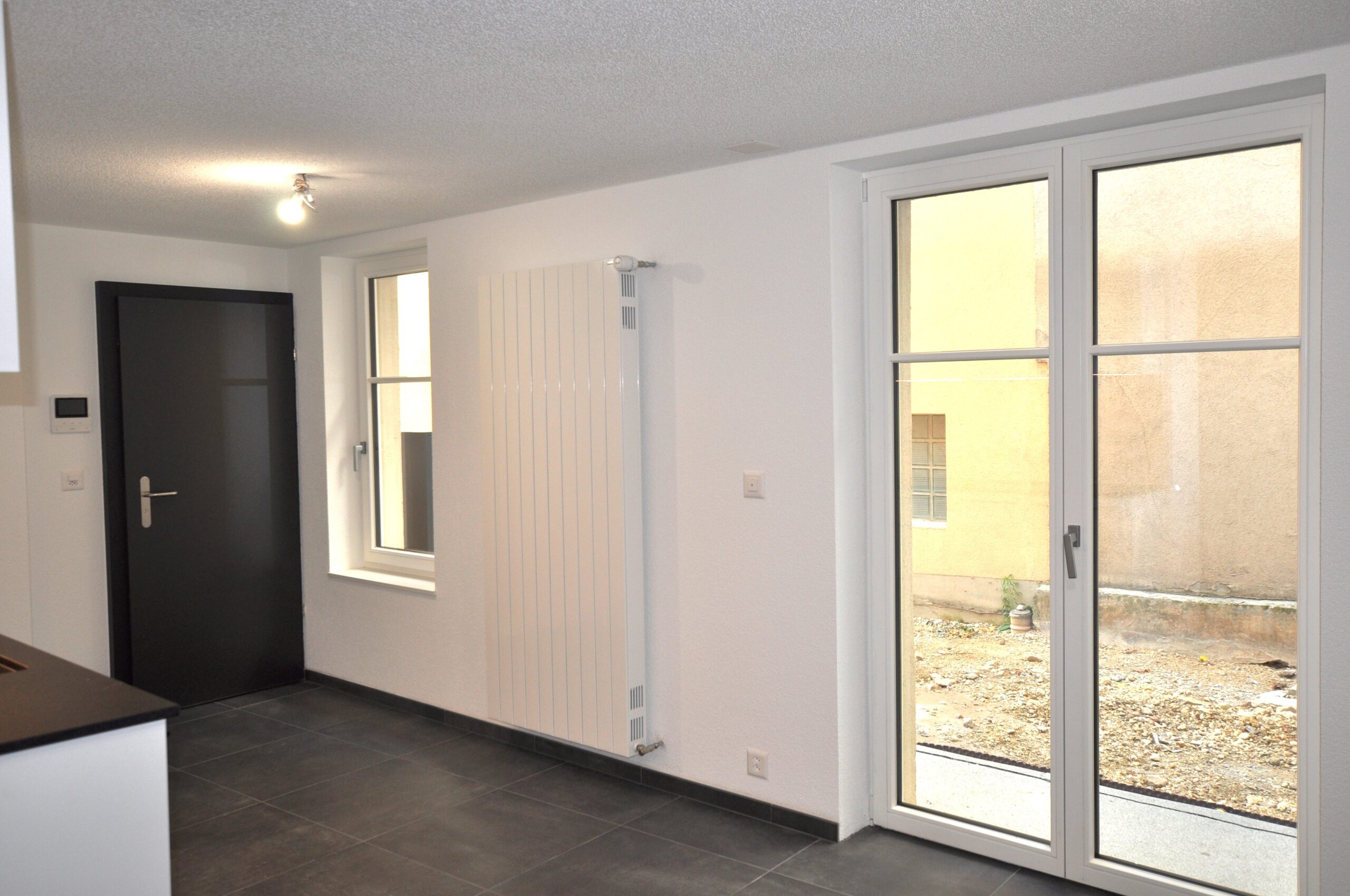 Heller Raum mit dunklem Boden und großen Fenstern
