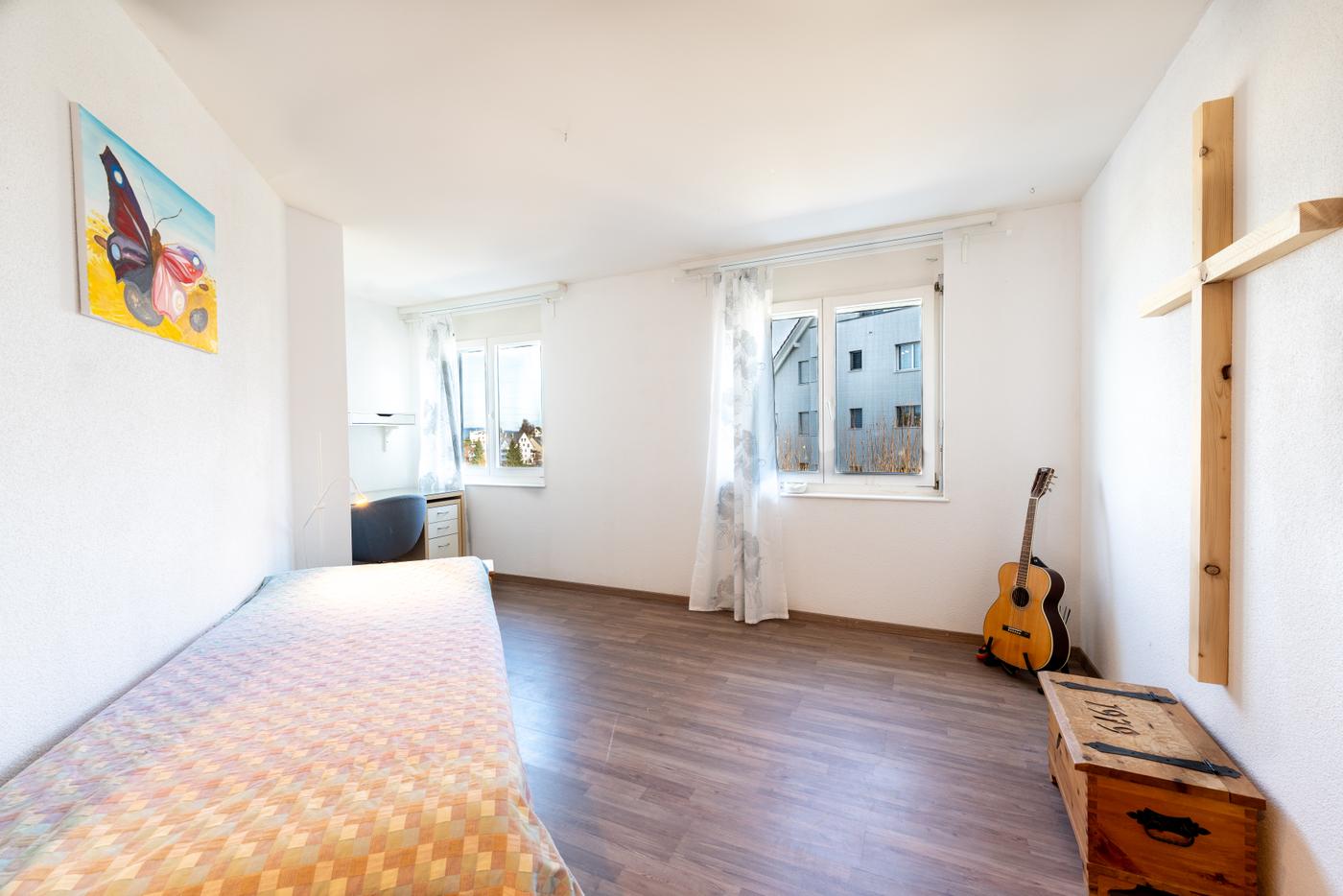 Helles Schlafzimmer mit Dachschräge und schlichtem Mobiliar