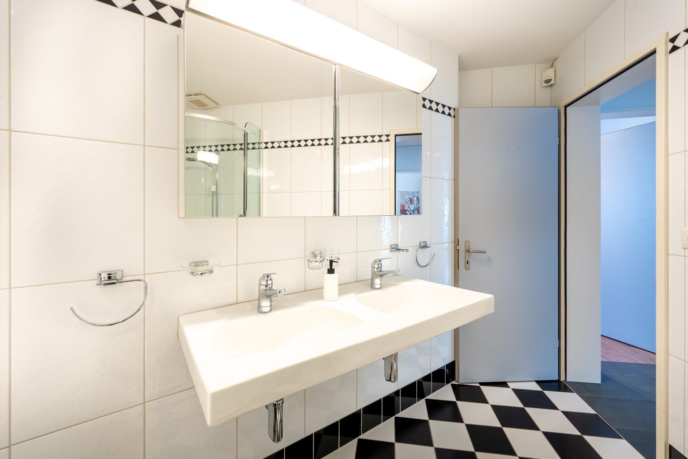 Modernes Badezimmer mit weißer Keramik und Schachbrettboden