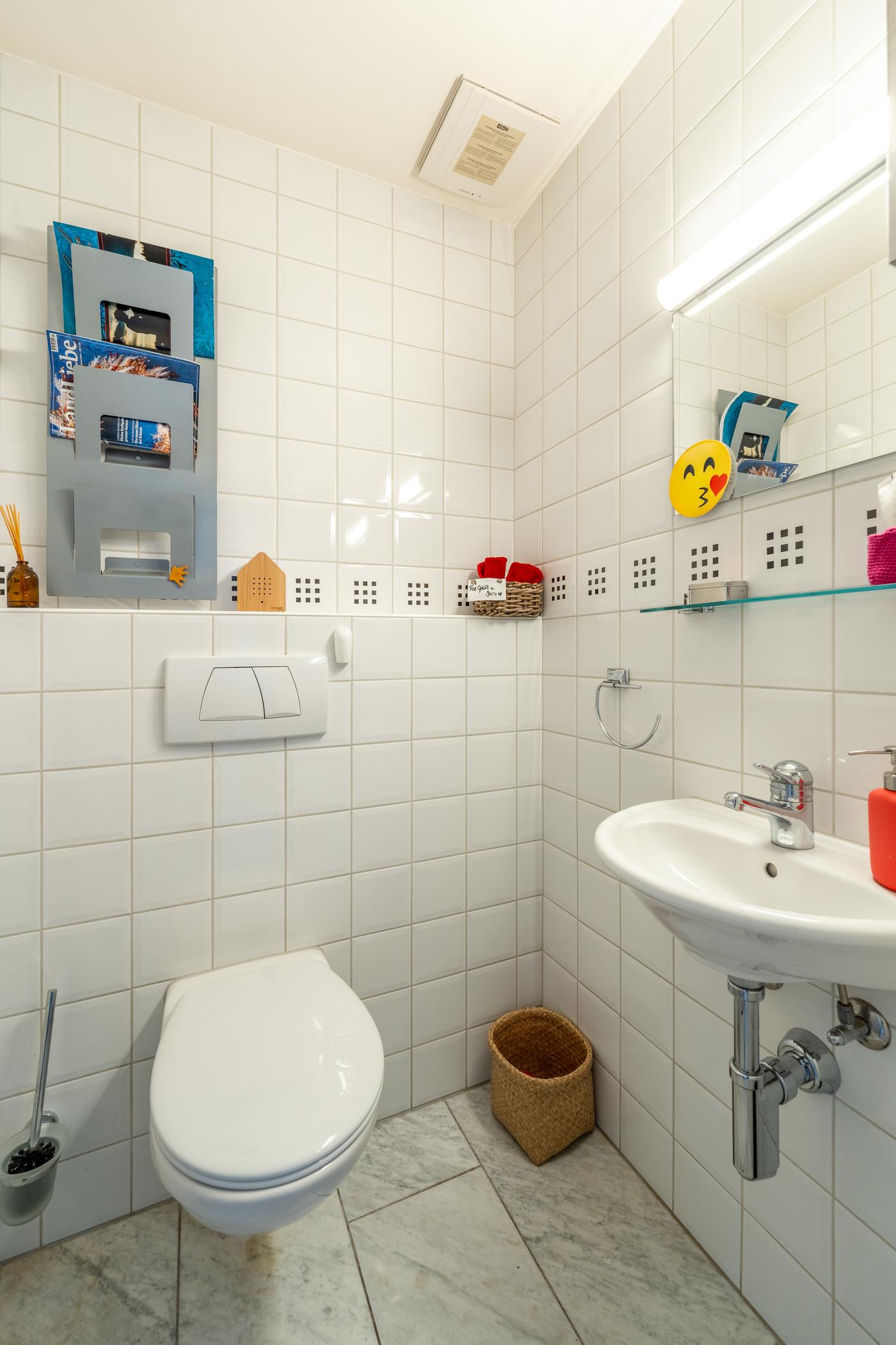Gäste-WC mit weißen Wandfliesen und Waschbecken