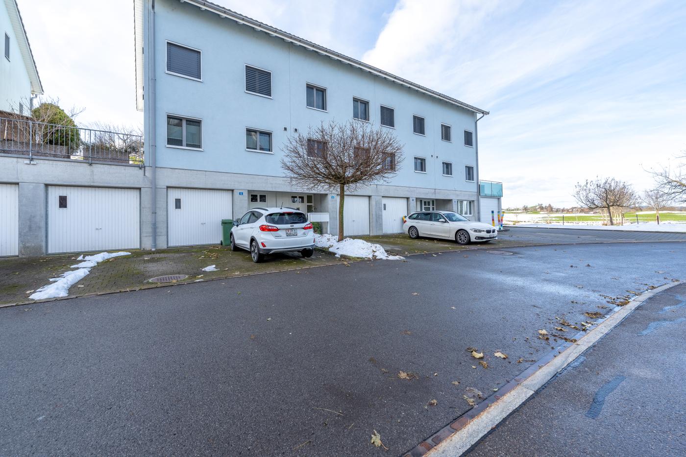 Mehrfamilienhaus mit Garagen und Straßenansicht