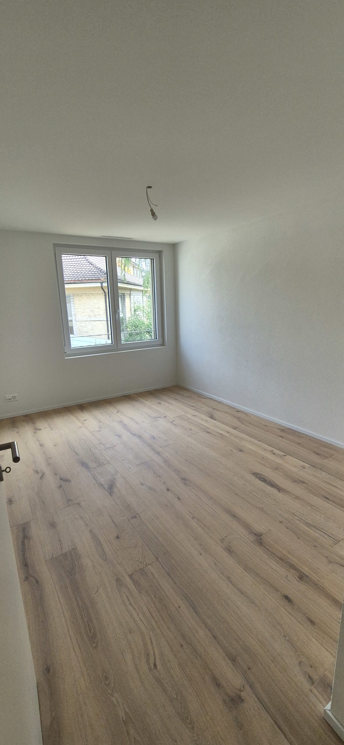 Leerer heller Raum mit Parkett und Fenster