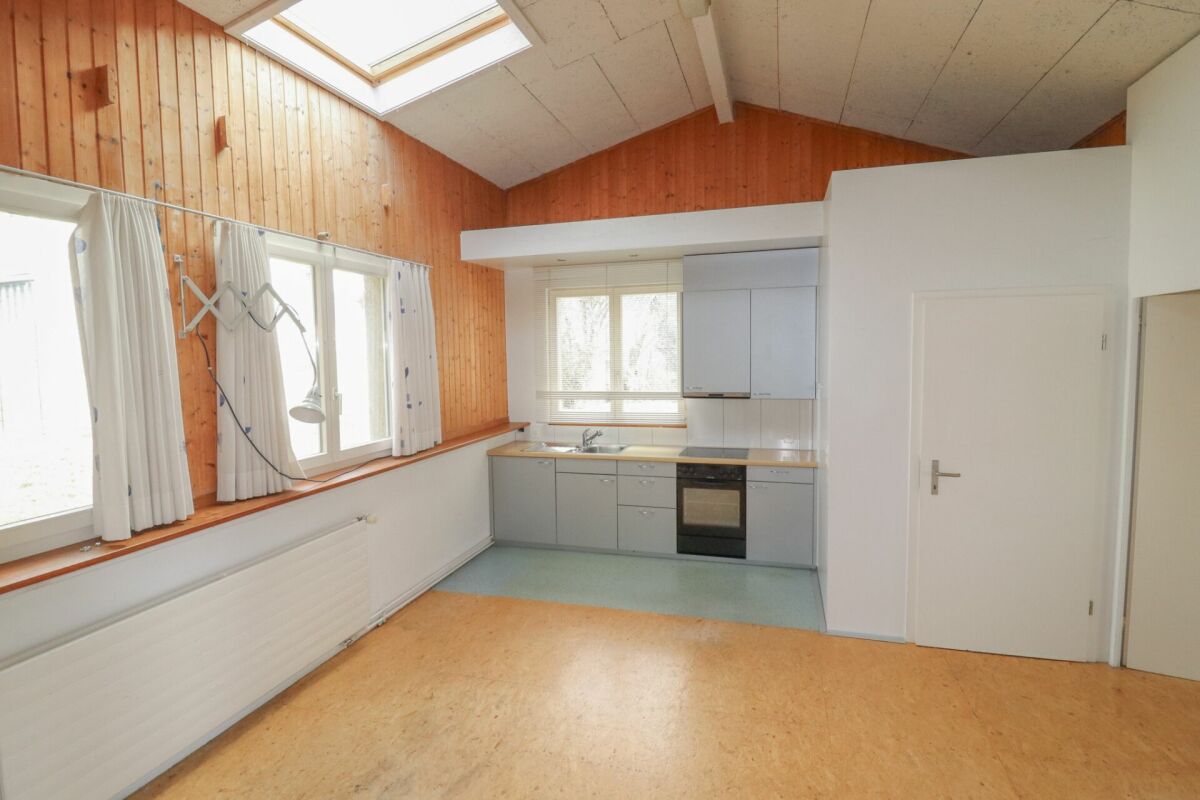 Kleiner Wohnraum mit Küchenzeile und Holzvertäfelung