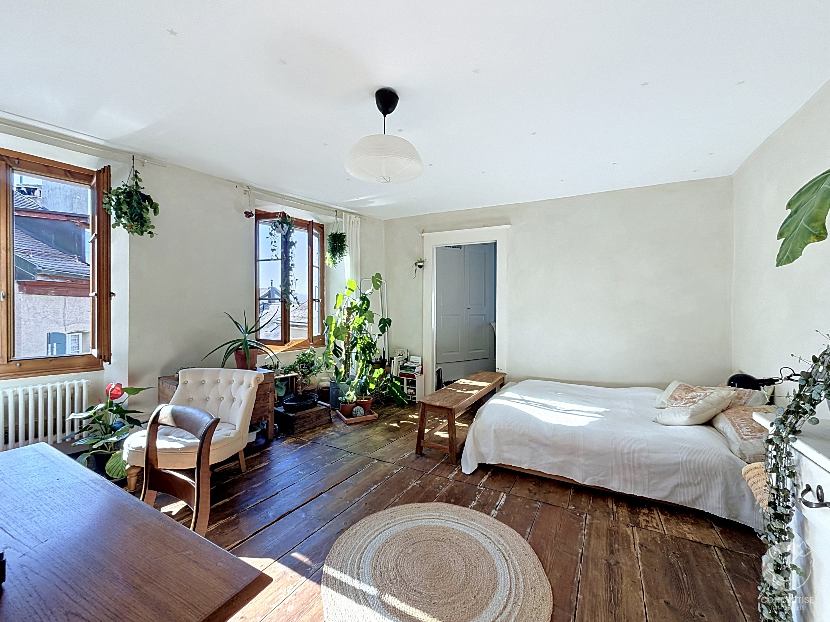 Helles Schlafzimmer mit Holzboden und vielen Pflanzen