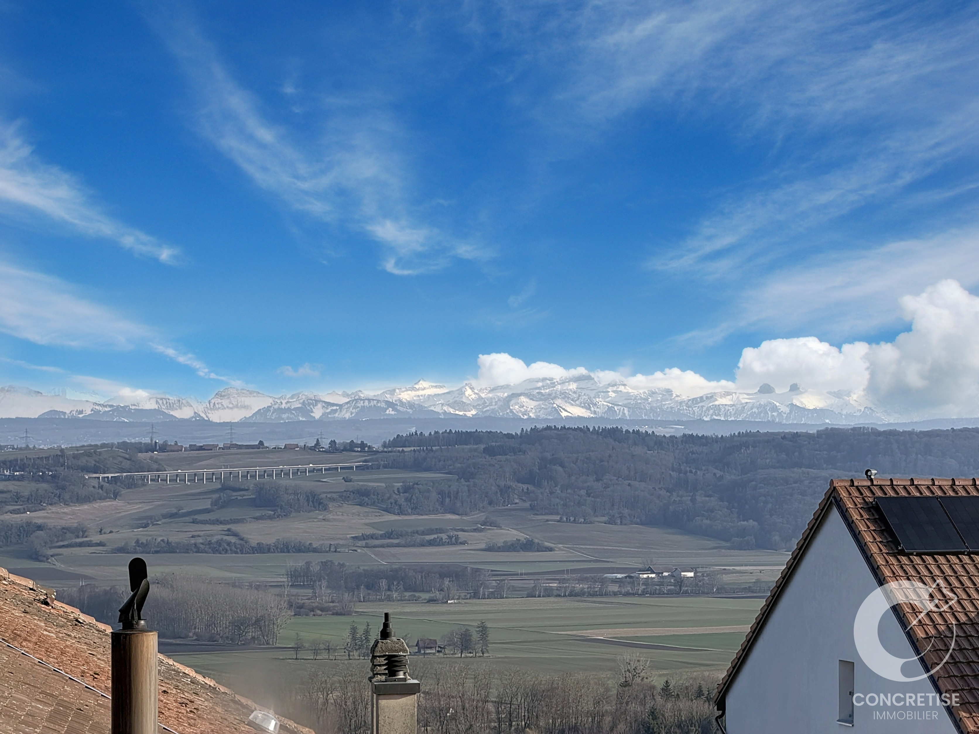Panoramablick auf Gebirge und Tal mit Dächern im Vordergrund