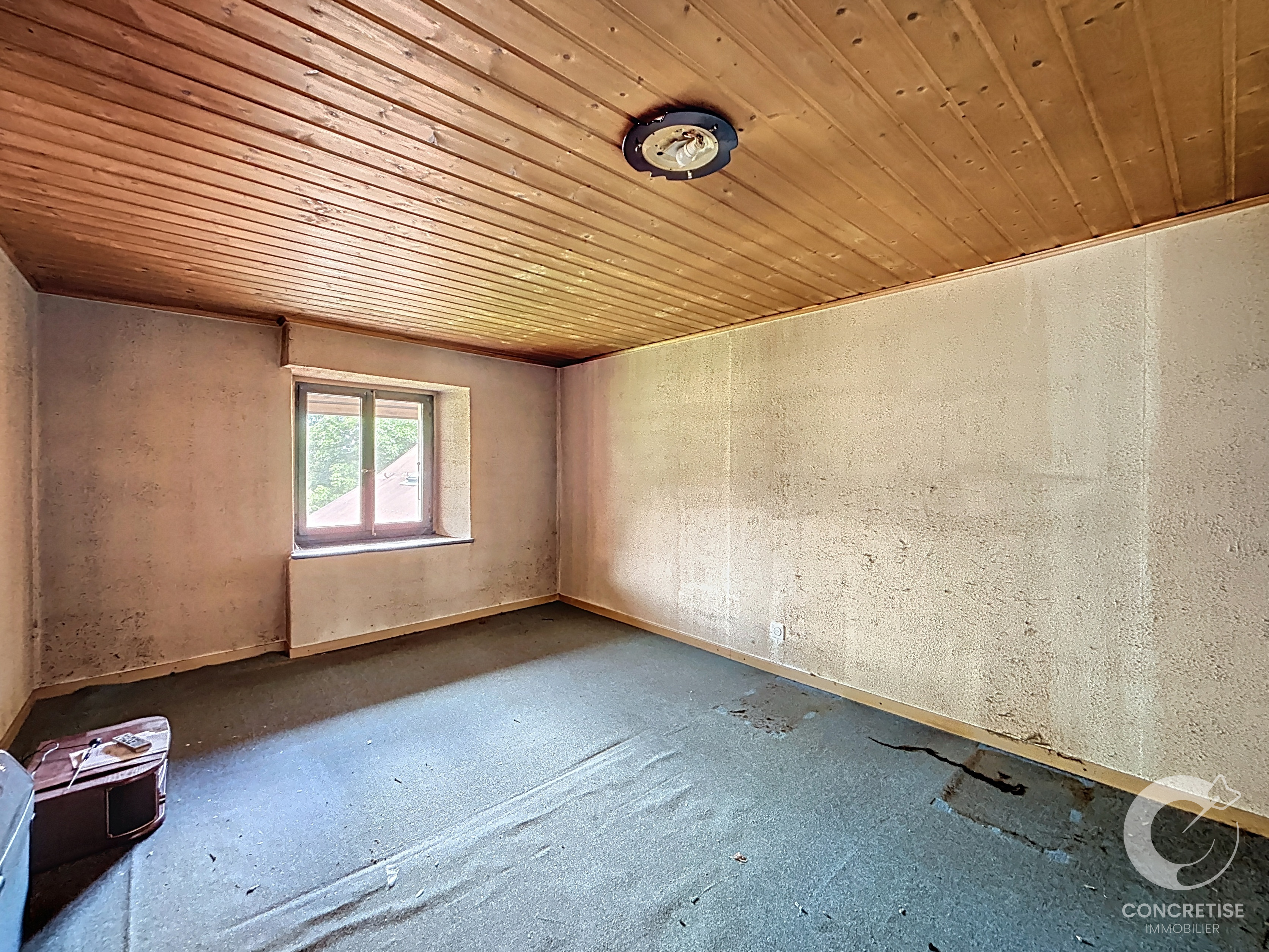 Leerer, renovierungsbedürftig wirkender Raum mit Holzdecke