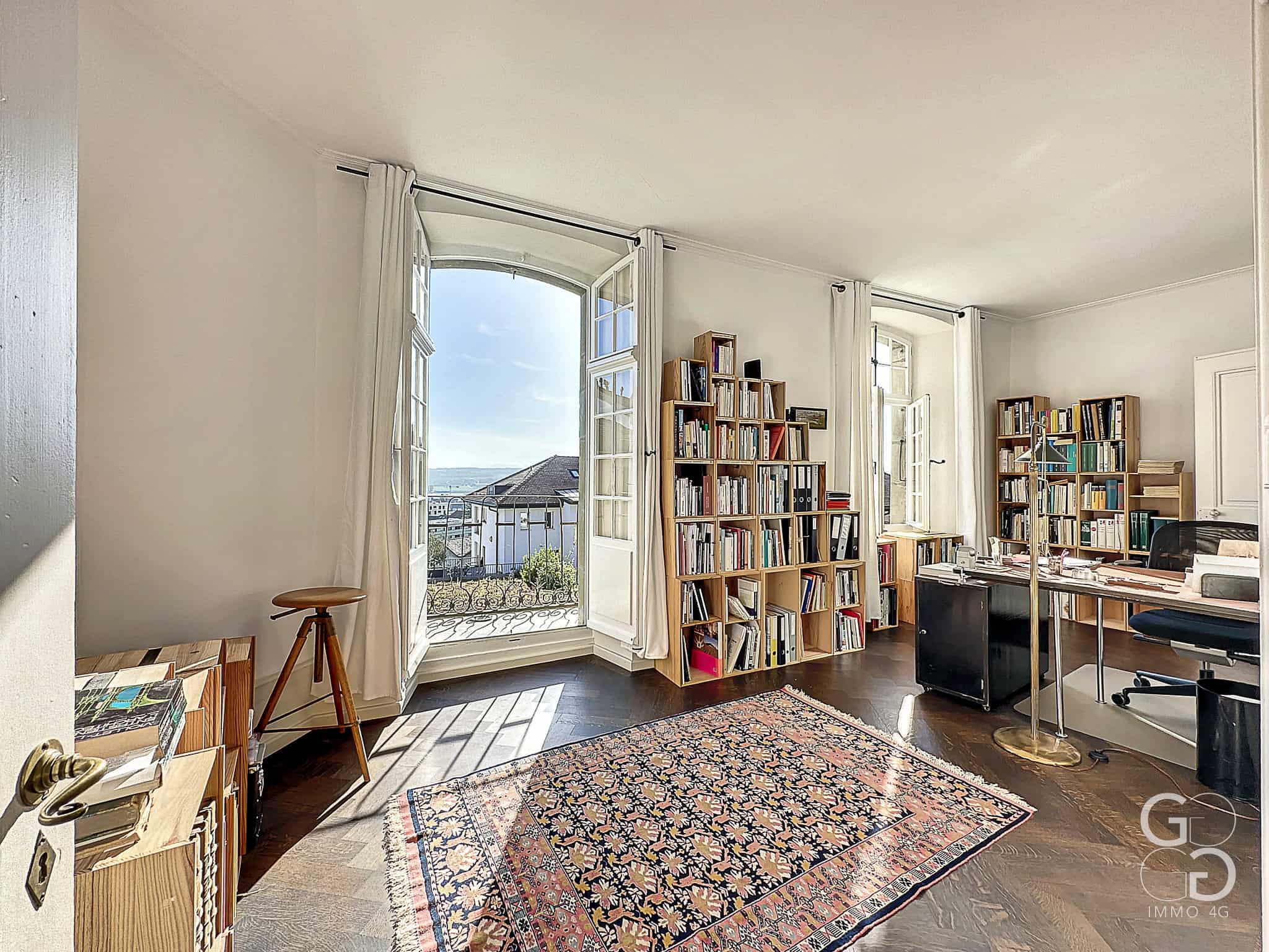Hell eingerichtetes Arbeitszimmer mit Balkonblick