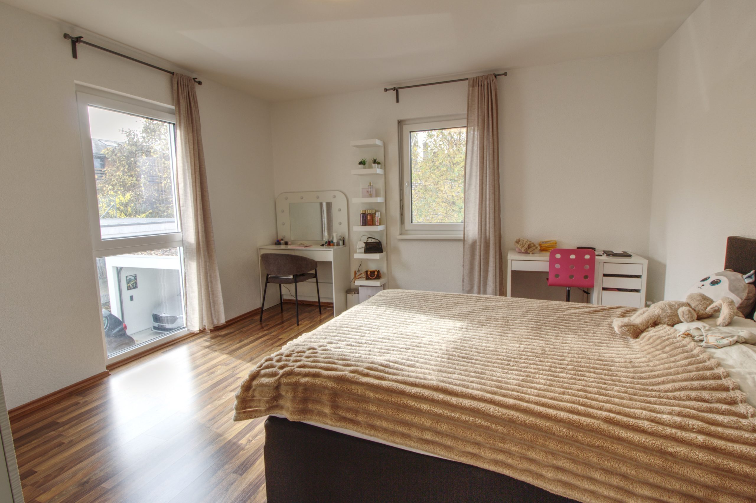 Helles Schlafzimmer mit zwei Fenstern und Schminktisch