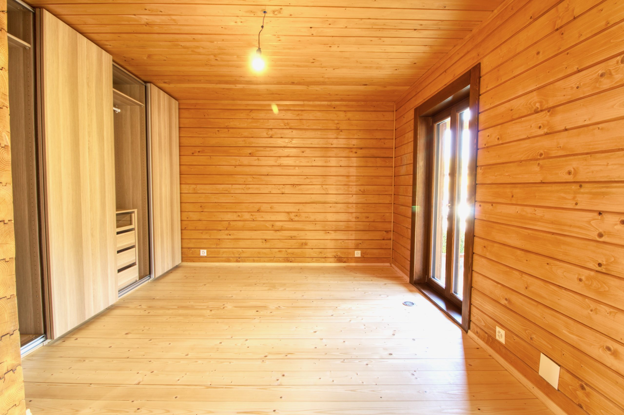 Holzverkleideter Raum mit Fenster und Einbauschrank