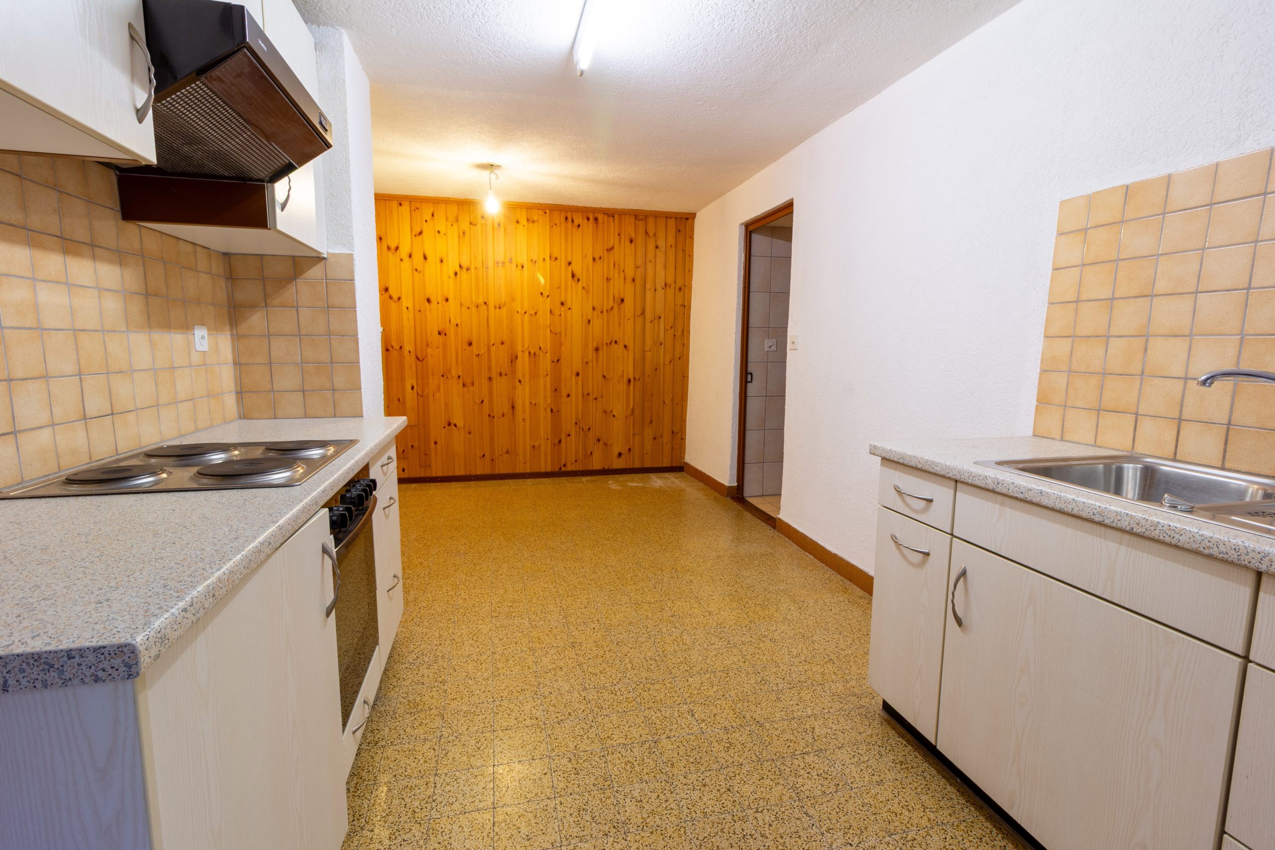 Kleine Einbauküche mit Fliesen und Holzwand