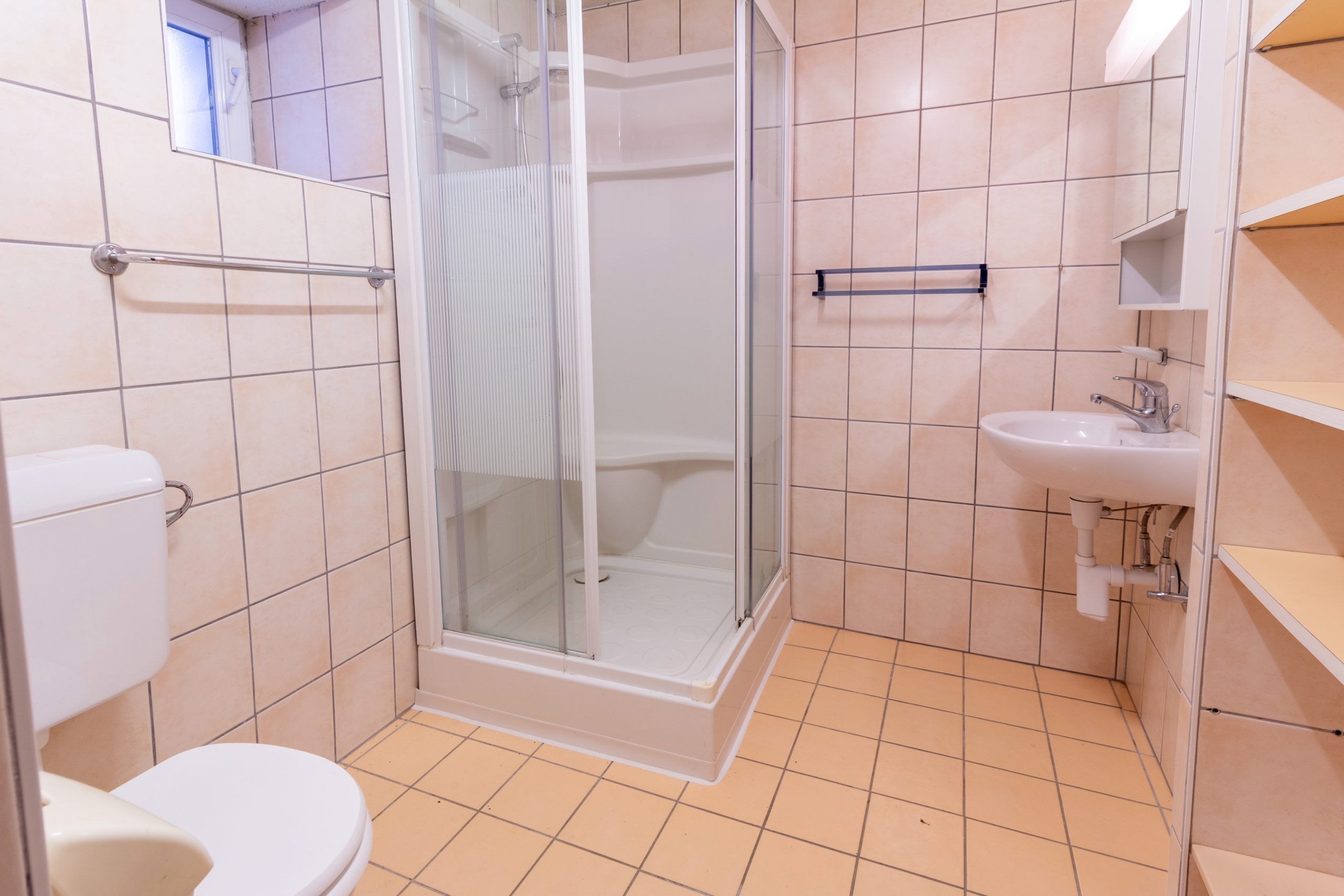 Kleines, gefliestes Badezimmer mit Dusche und Waschbecken