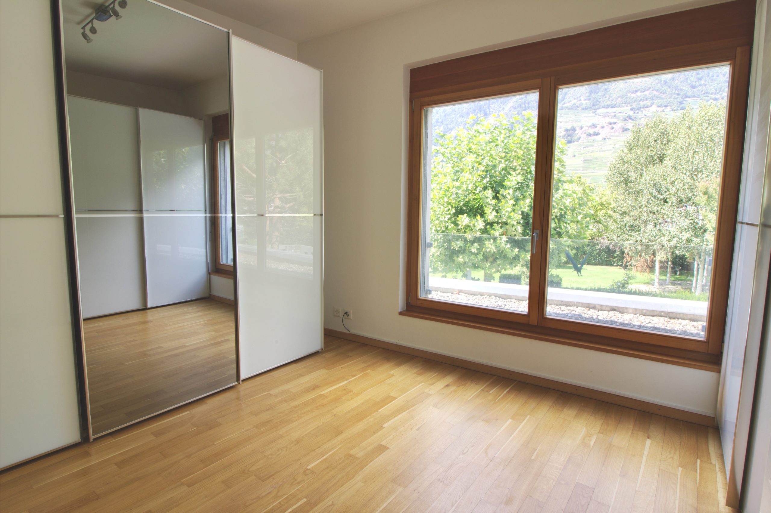 Helles Schlafzimmer mit großem Fenster und Einbauschrank