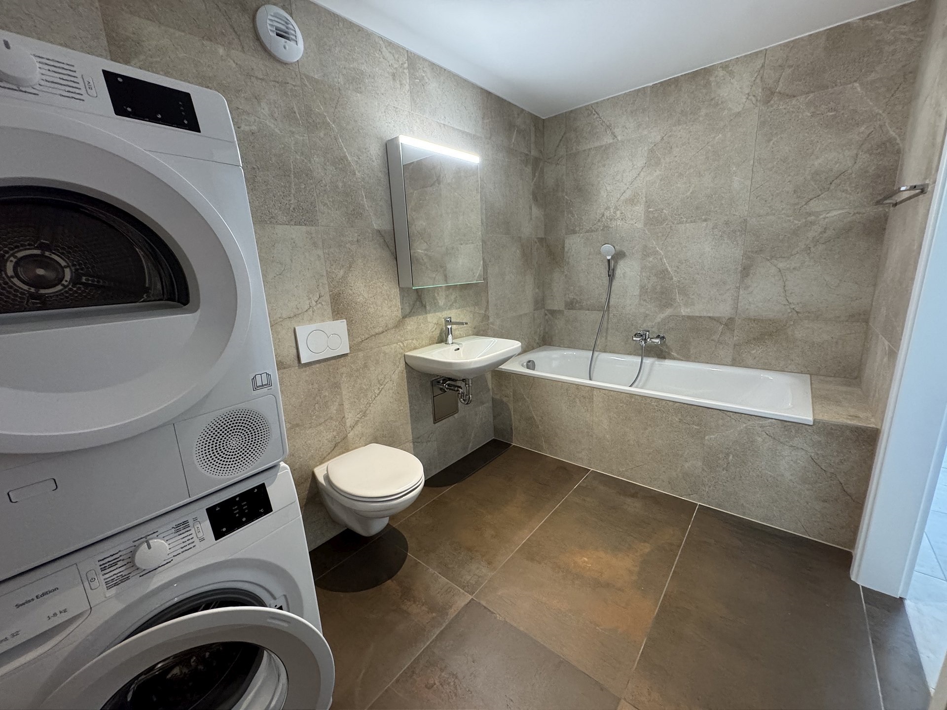 Modernes Badezimmer mit Waschmaschine und Badewanne