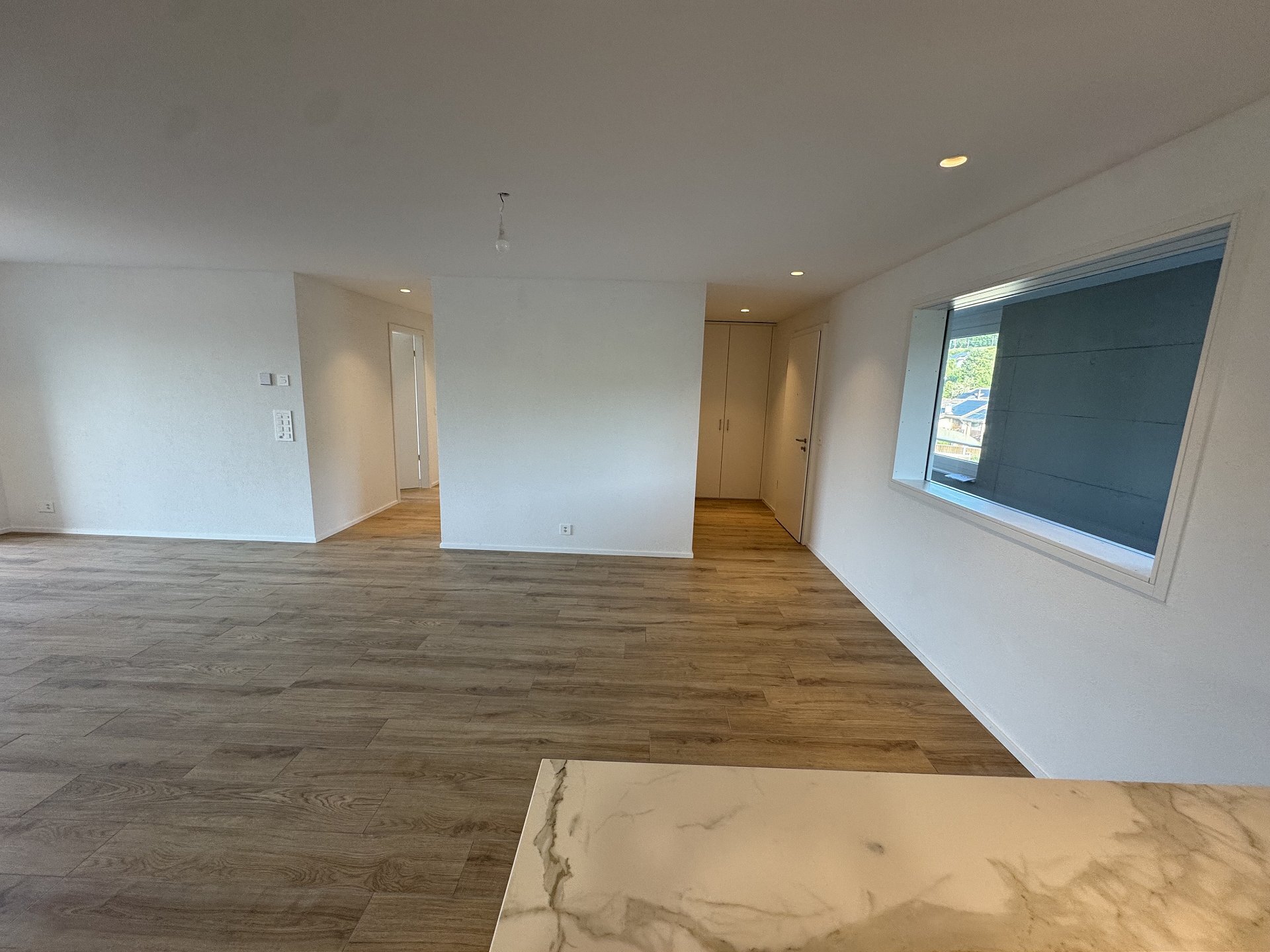 Heller, leerer Wohnraum mit Holzoptikboden