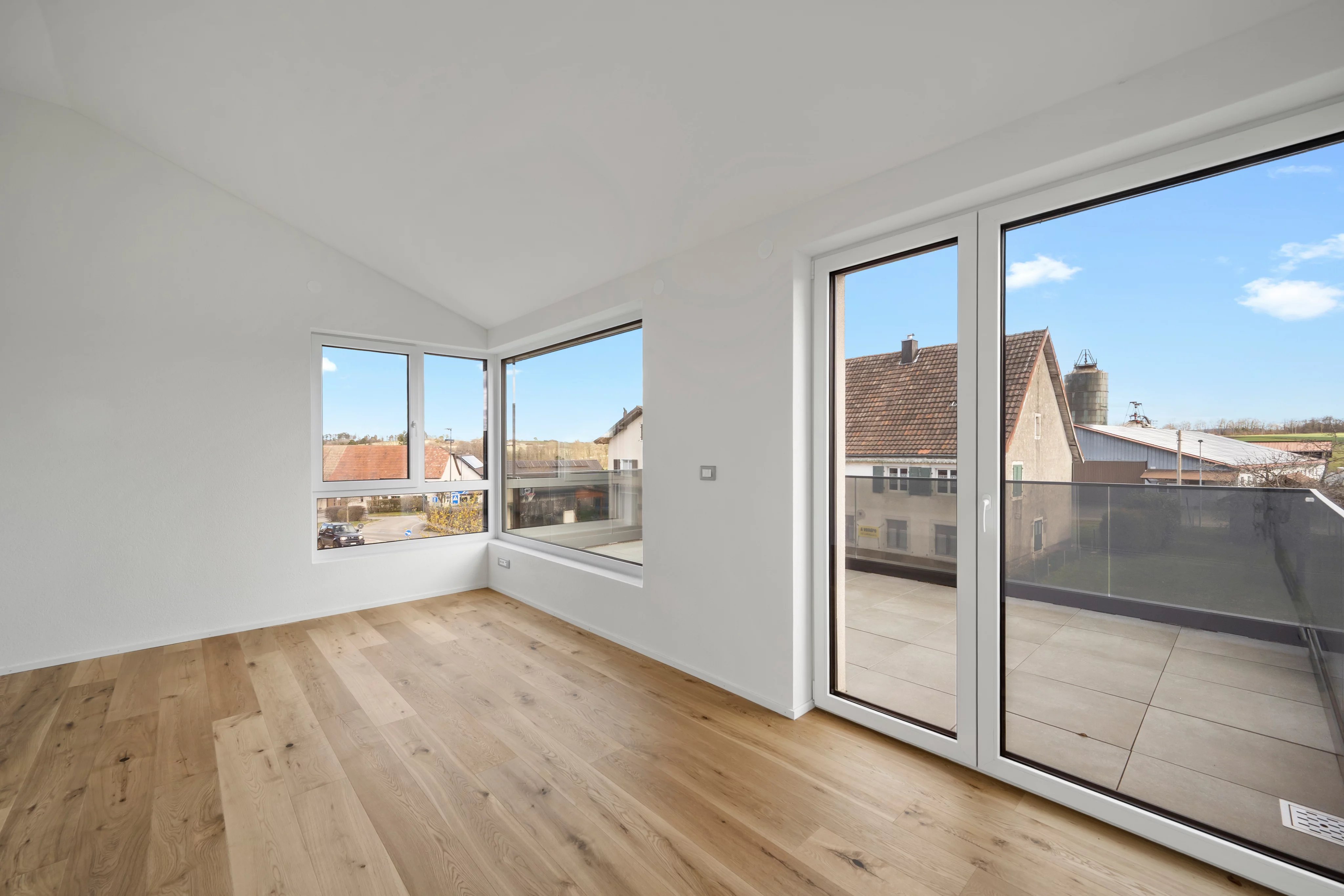 Heller leerer Raum mit großen Fenstern und Balkon