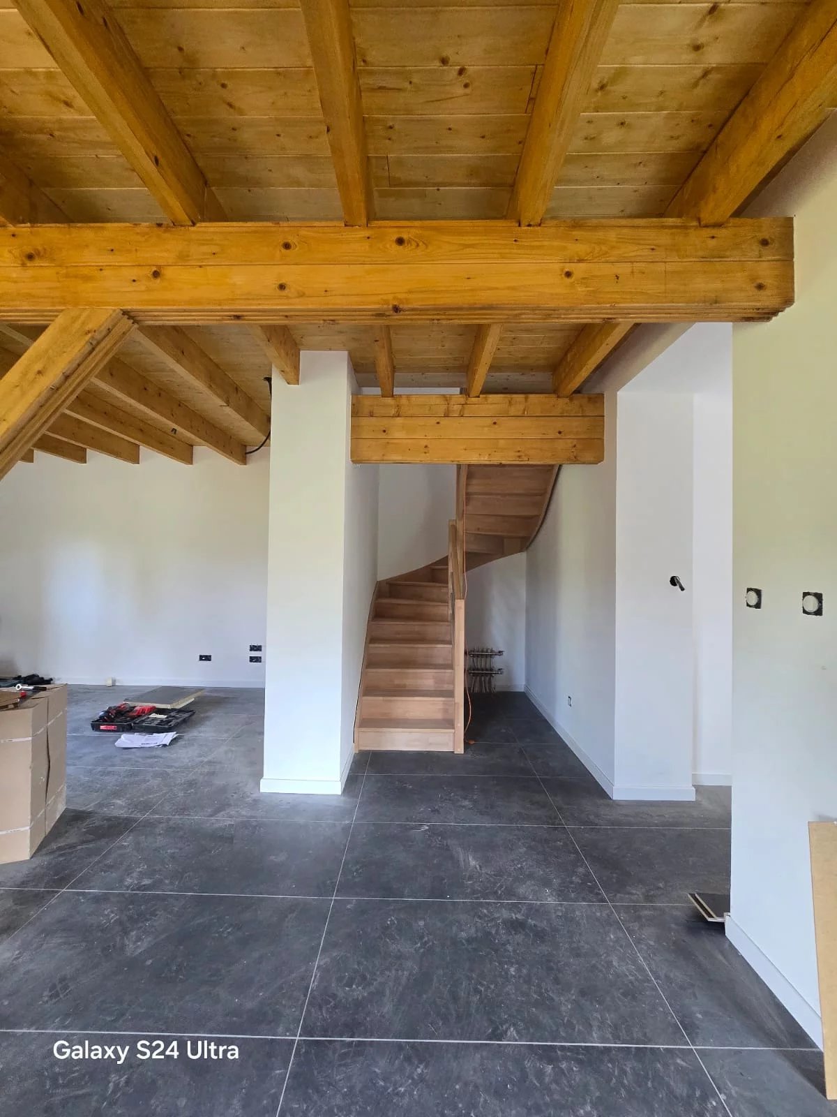 Innenraum mit sichtbarer Holzdecke und Treppe