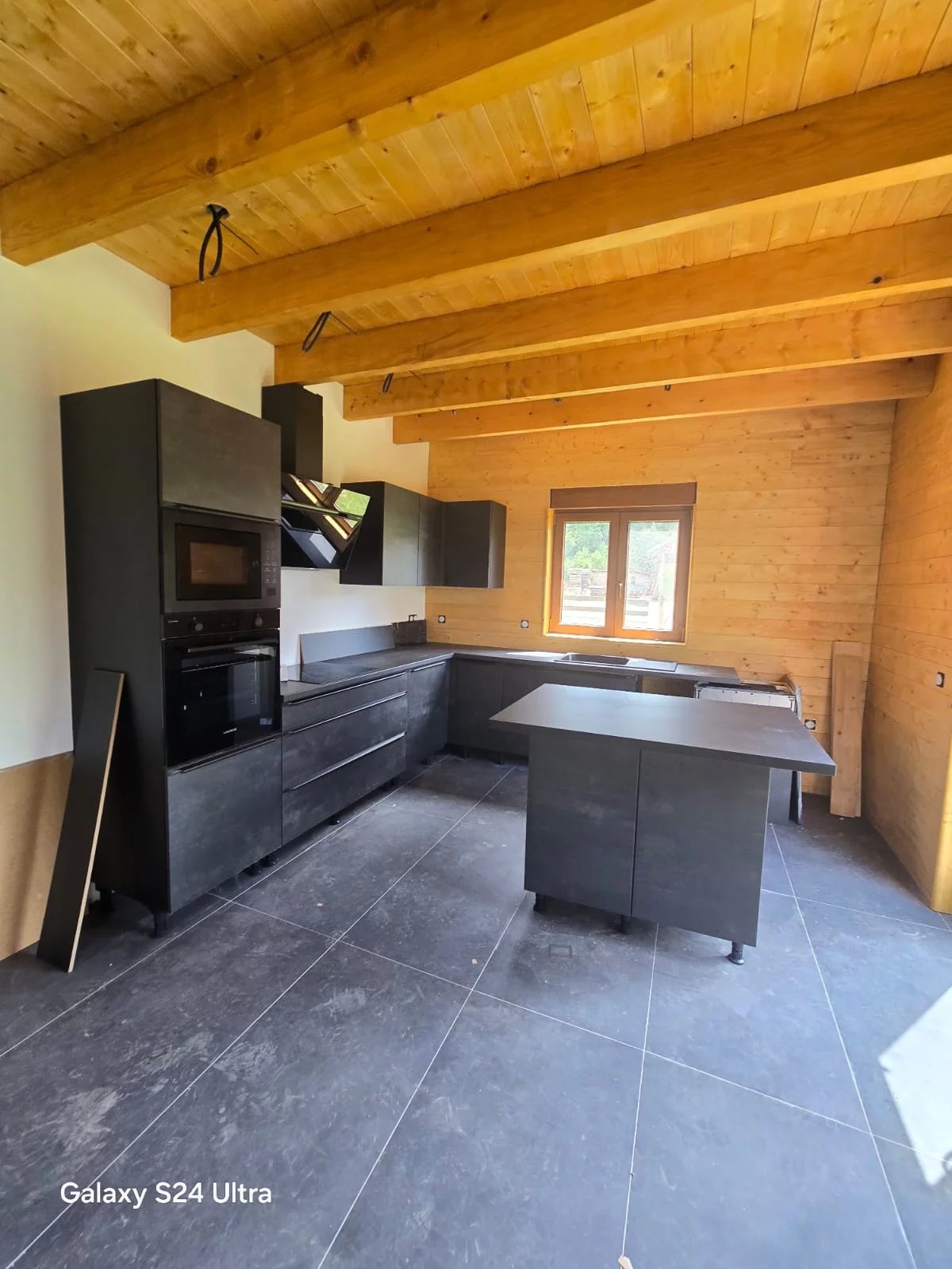 Offene Küche mit Holzdecke und dunkler Kücheninsel