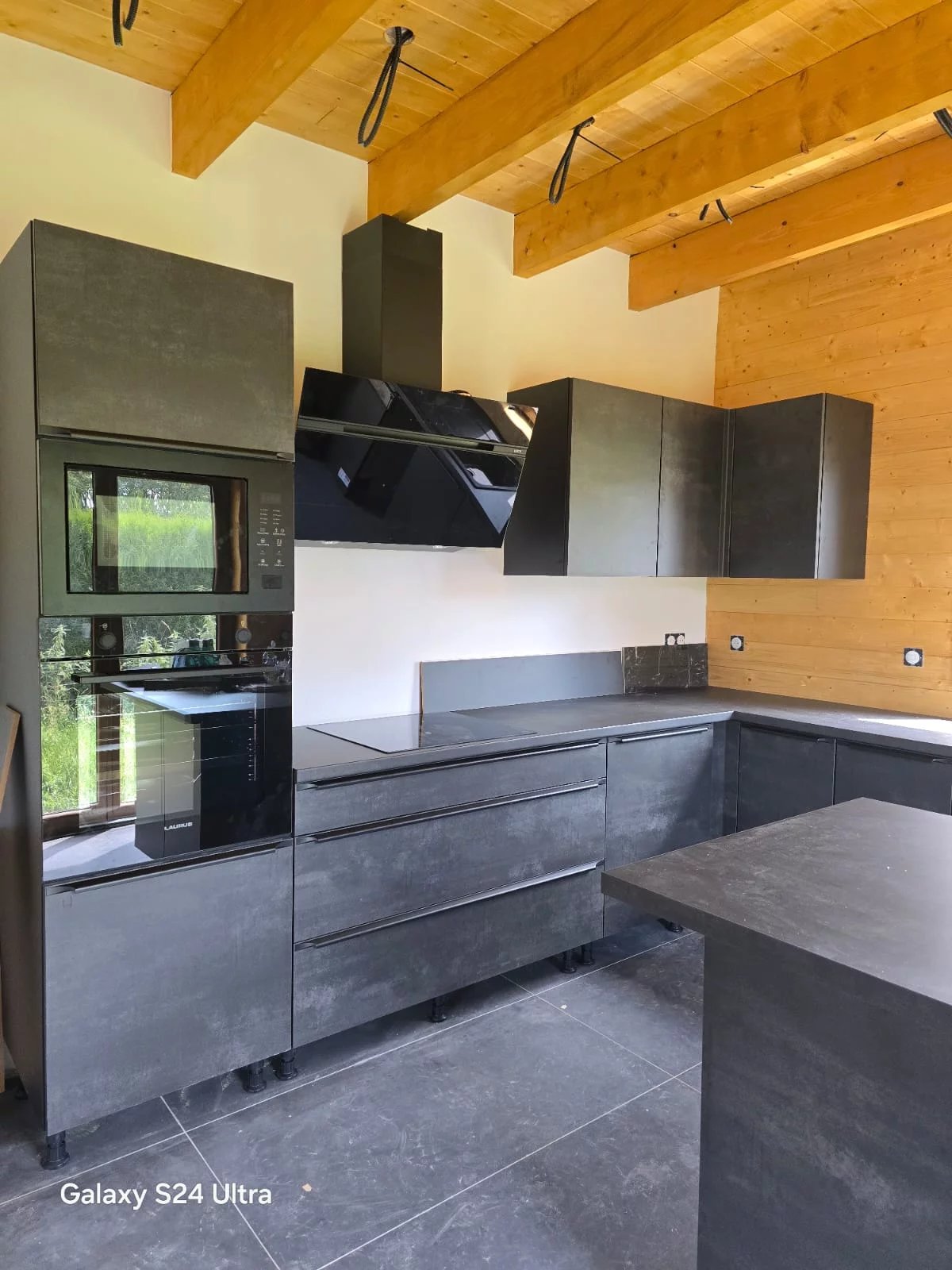 Moderne Küche mit dunklen Fronten und Holzdecke