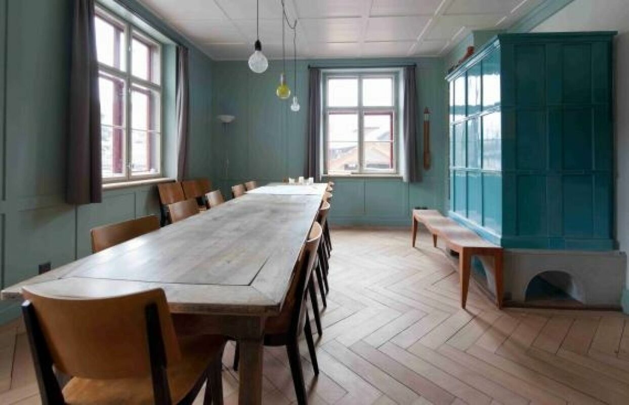 Esszimmer mit langem Holztisch und türkisfarbenem Ofen