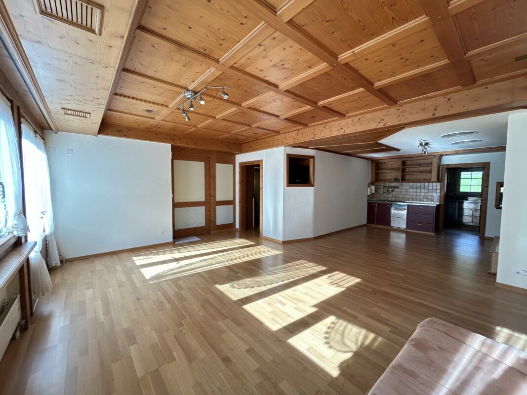 Großer Wohnraum mit Holzdecke und Küchenbereich