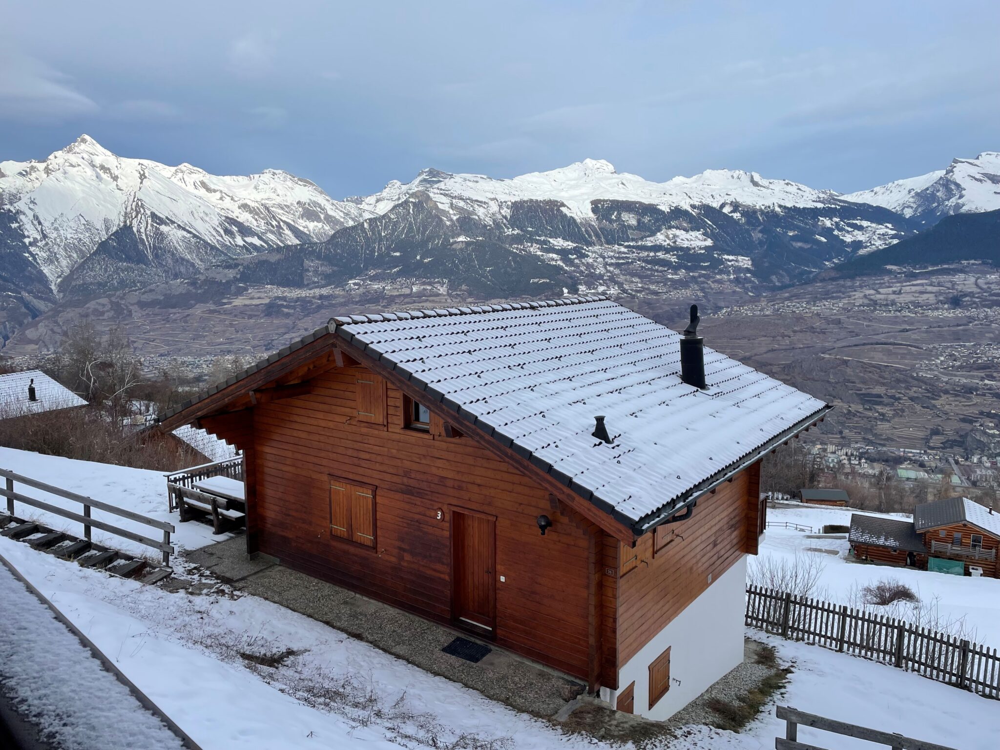 Verschneites Holzhaus mit Alpenpanorama
