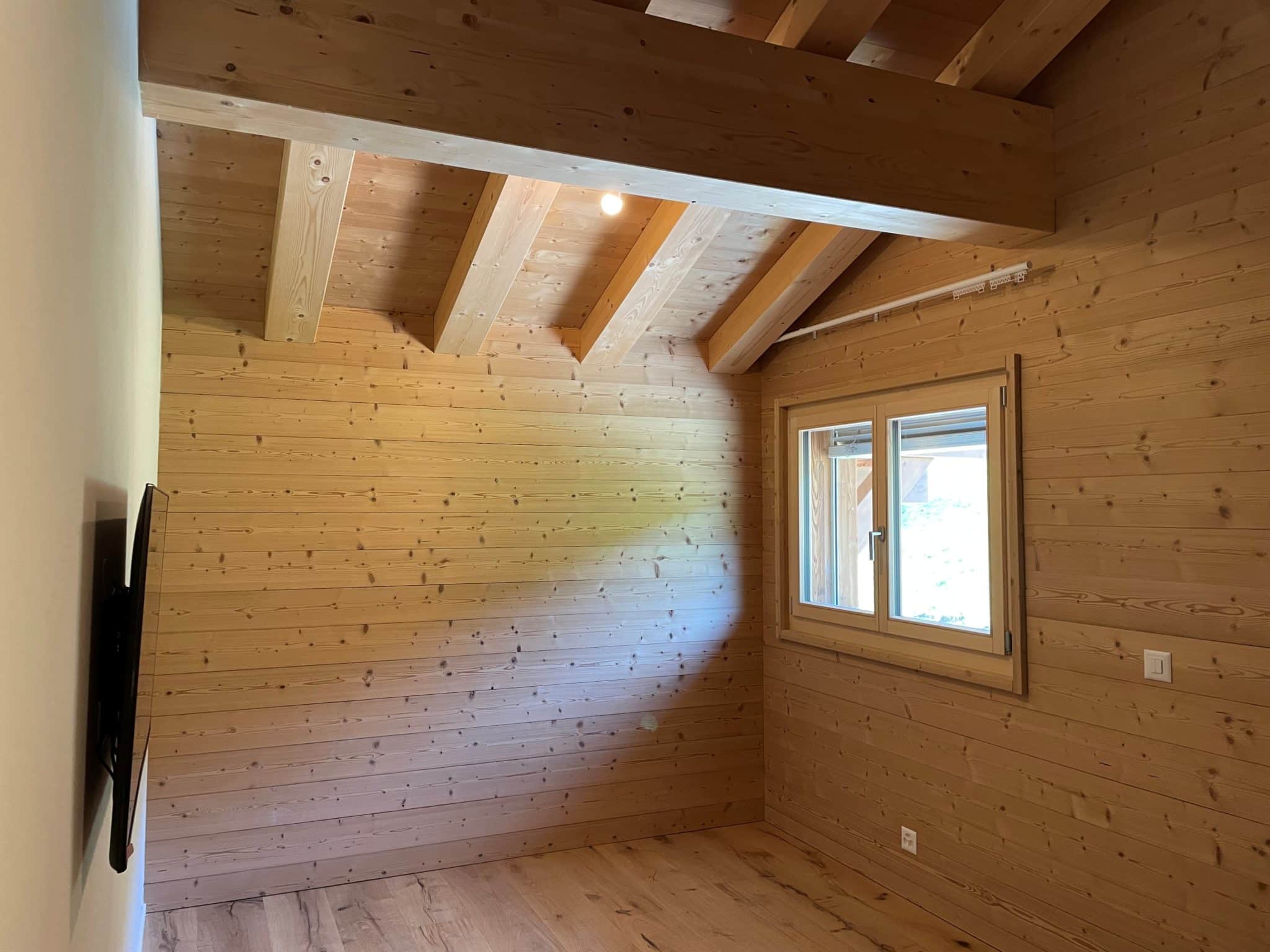 Holzverkleideter Raum mit sichtbaren Deckenbalken