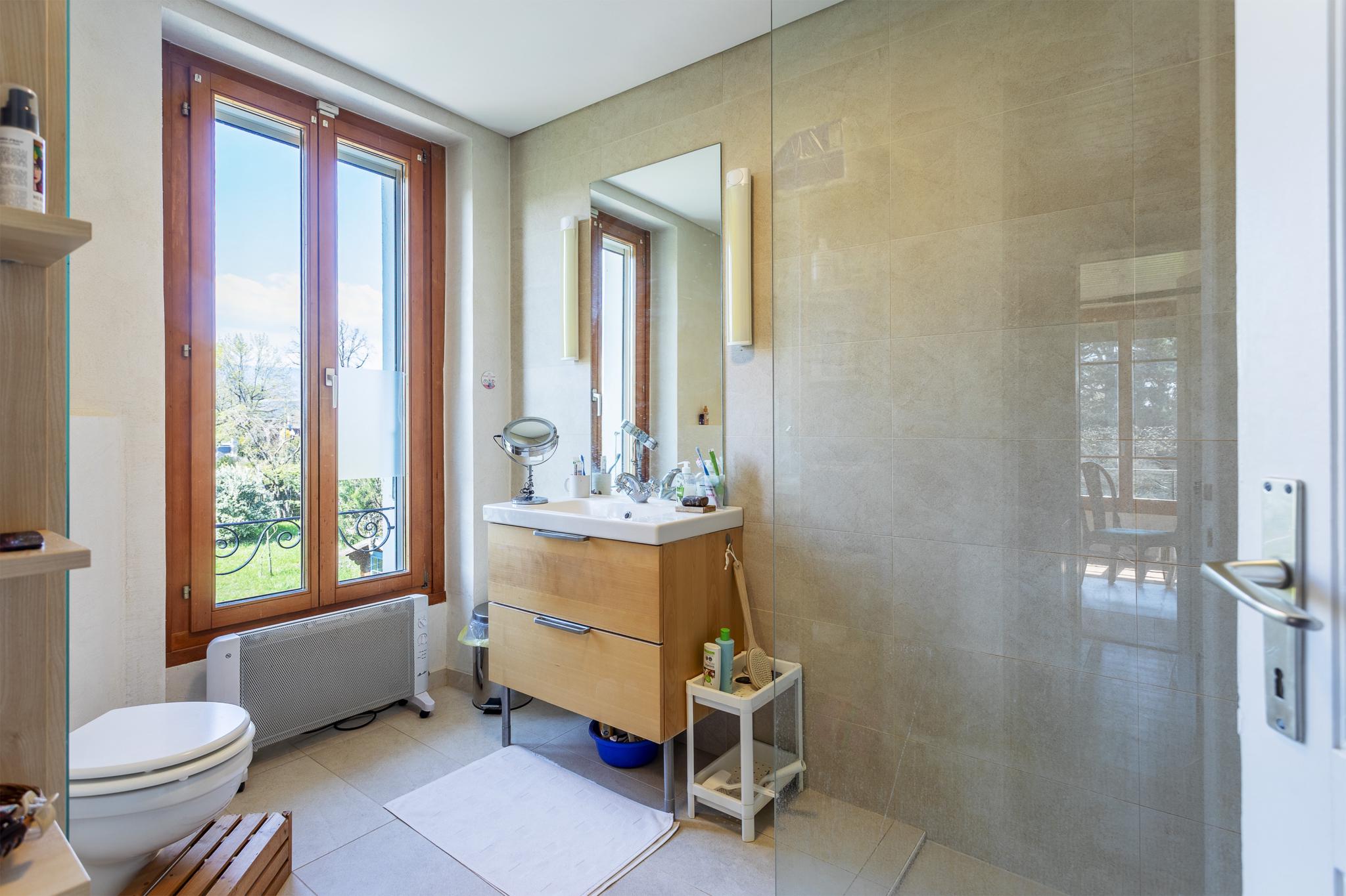 Helles Badezimmer mit großen Holzfenstern und Glasdusche