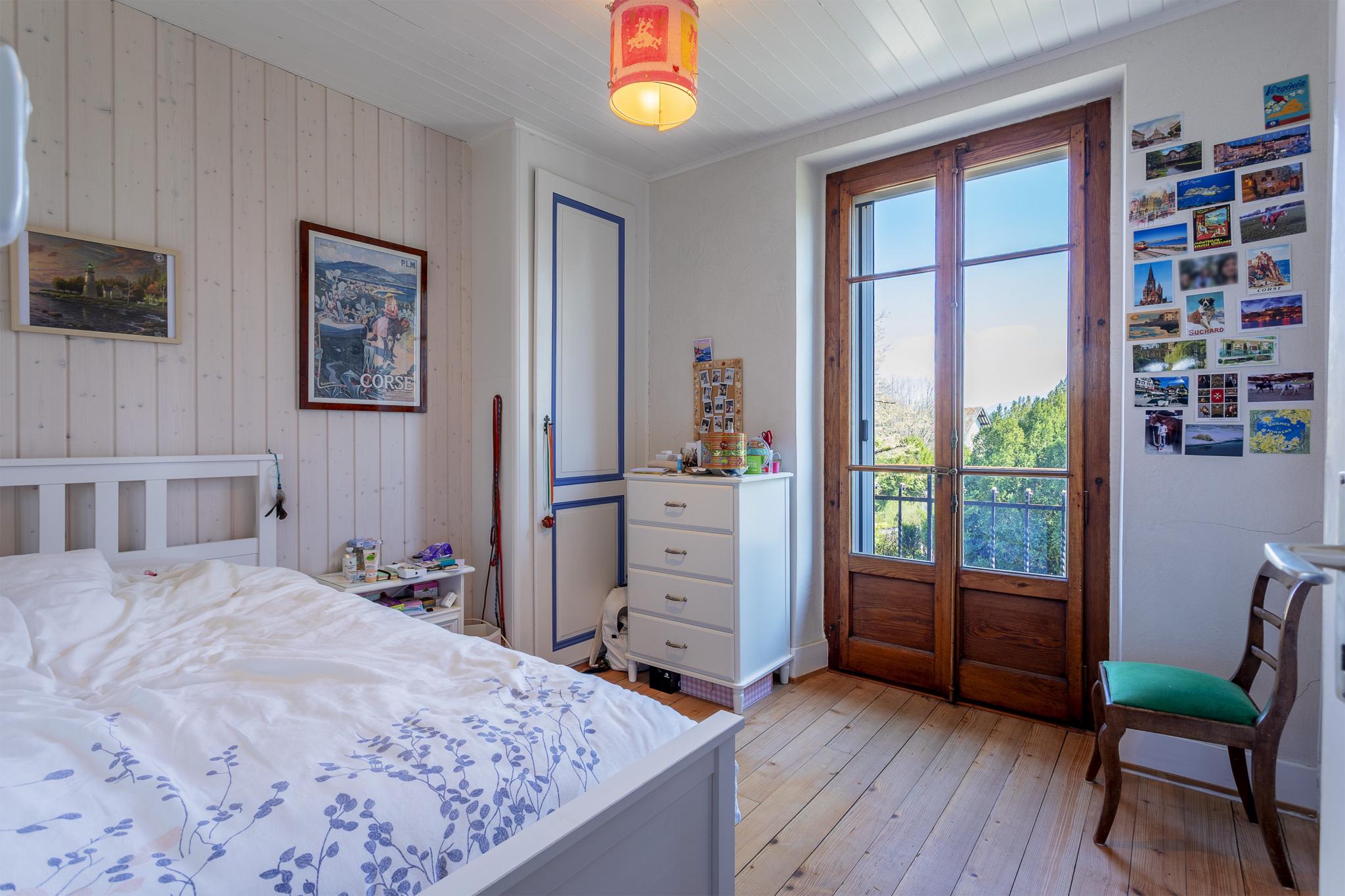 Helles Schlafzimmer mit Holzfenstertür und Blick ins Grüne