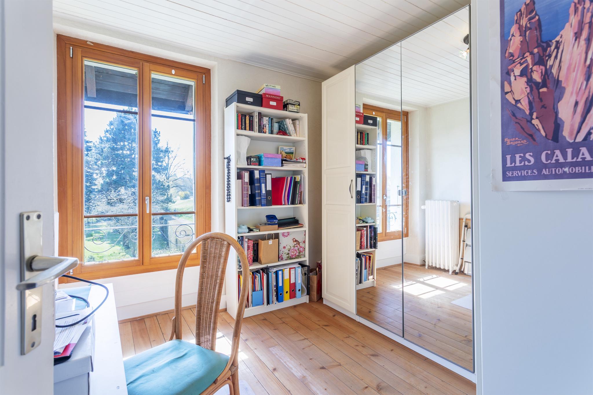 Helles Arbeitszimmer mit Holzfenstern und Spiegelkleiderschrank