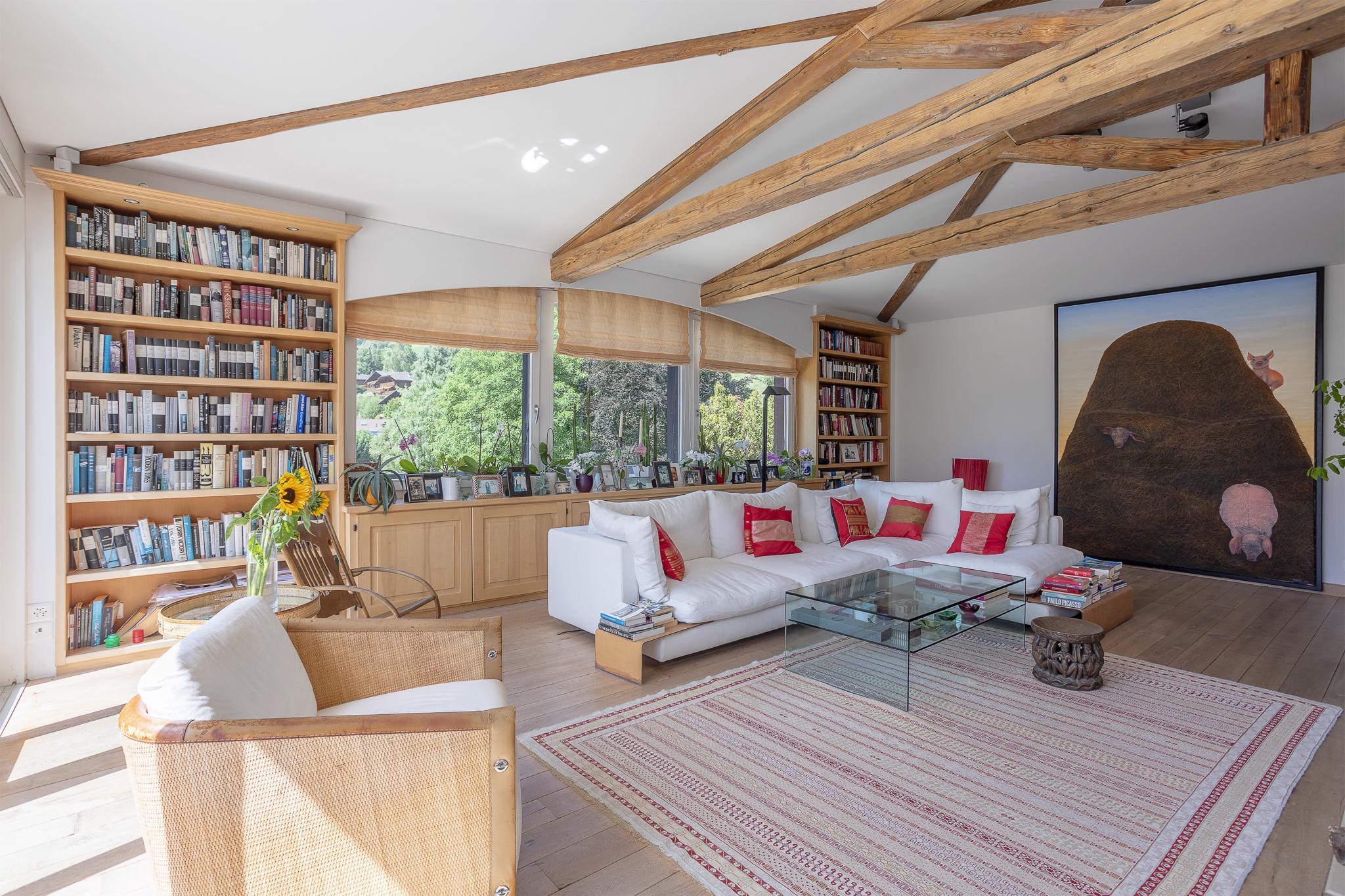 Heller Wohnraum mit sichtbaren Holzbalken und Bücherwand