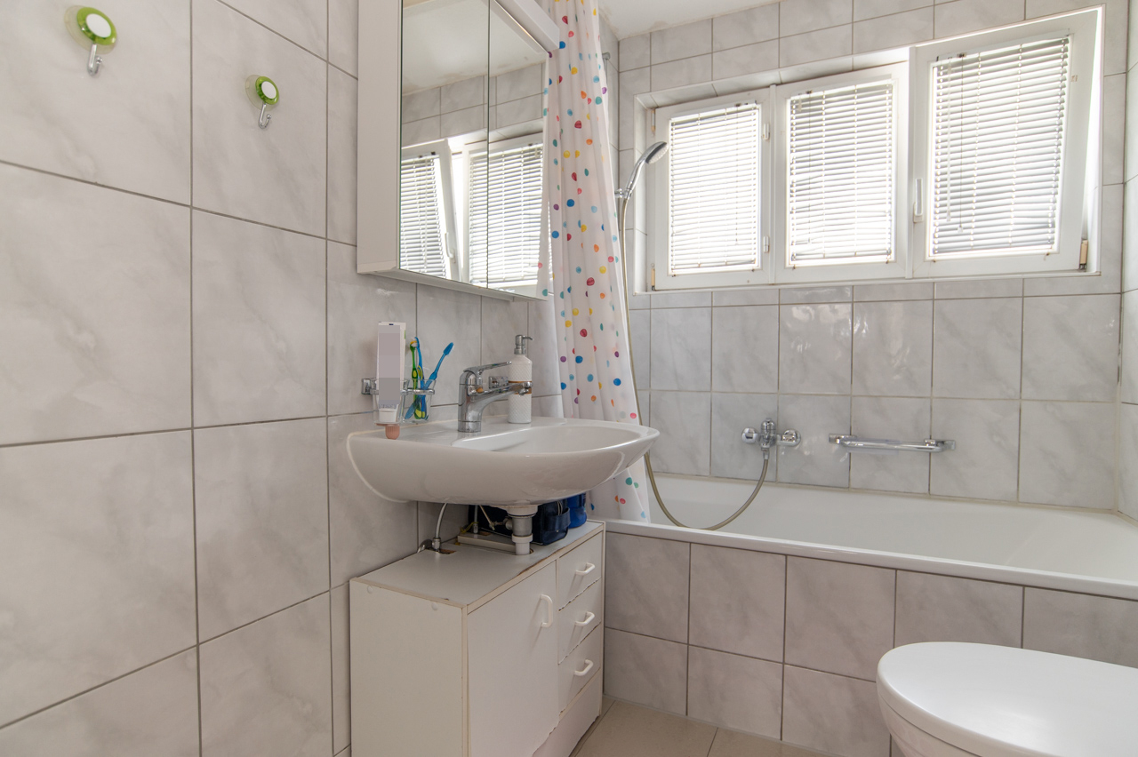 Badezimmer mit Badewanne und Fensterjalousien