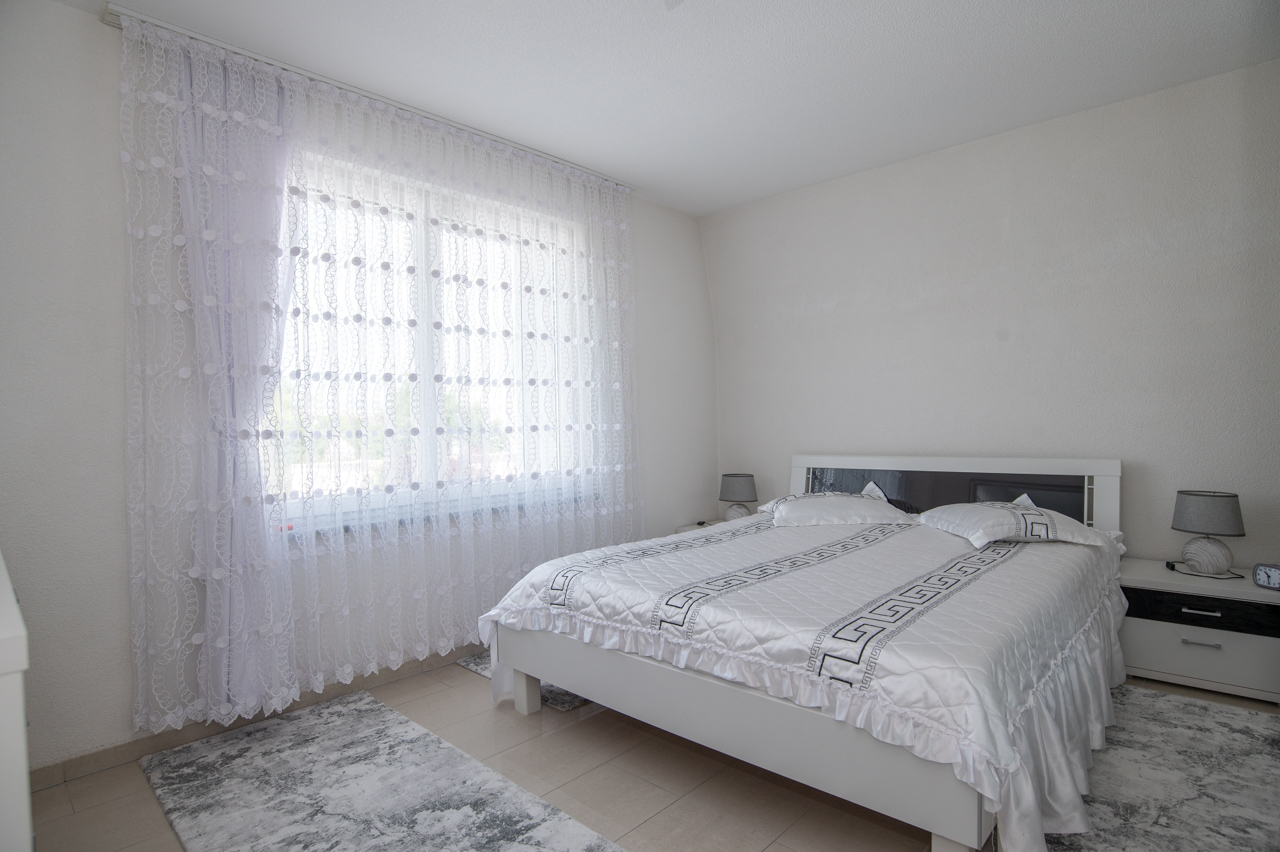 Helles Schlafzimmer mit Doppelbett und Fenster