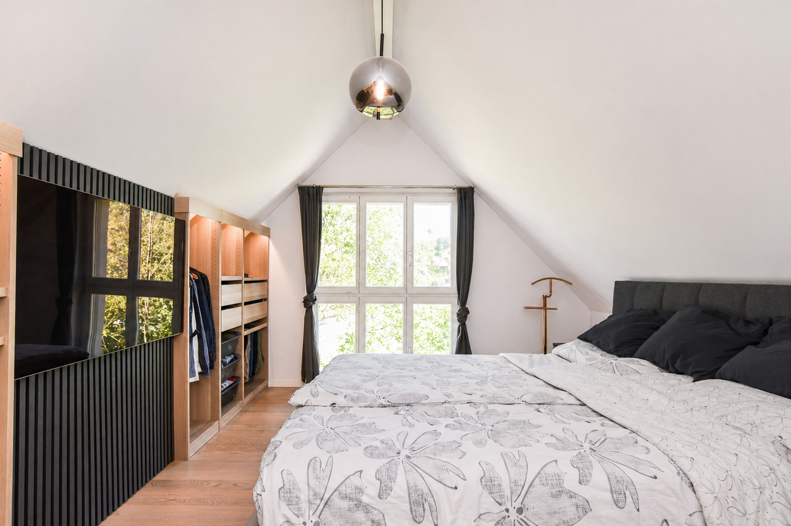 Dachgeschoss-Schlafzimmer mit Fensterfront und offener Kleideraufbewahrung