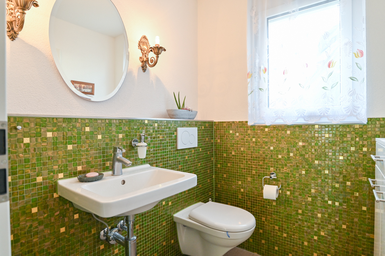 Gäste-WC mit grünem Mosaik und Fenster