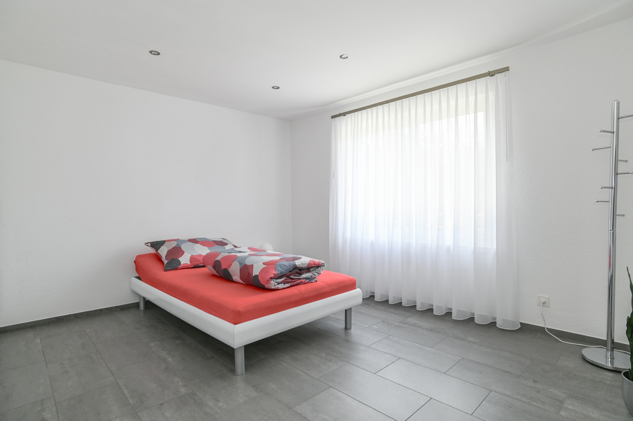 Minimalistisches Schlafzimmer mit Bett und Tageslichtfenster