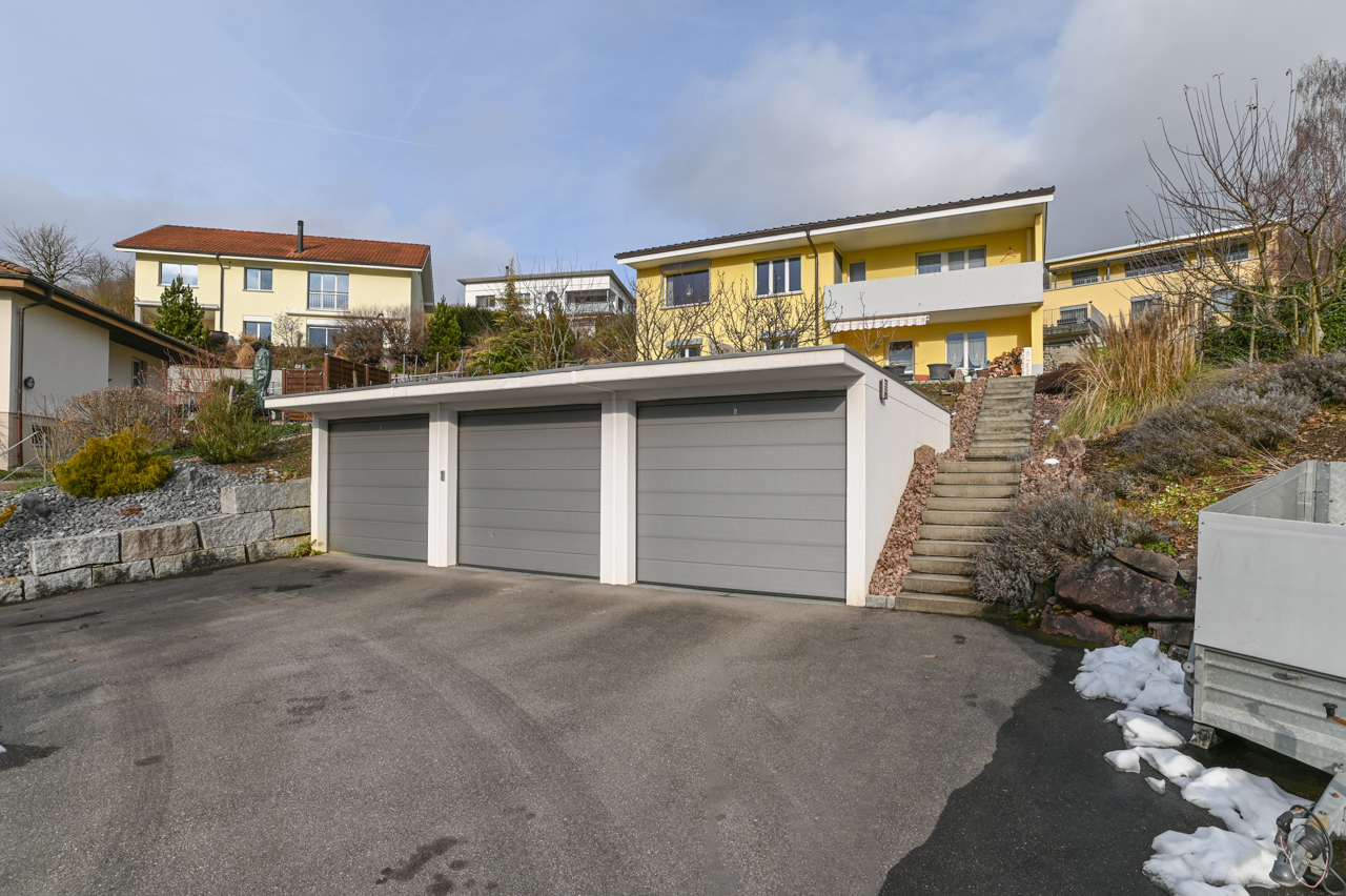 Außenansicht mit Garagenhof am Hang