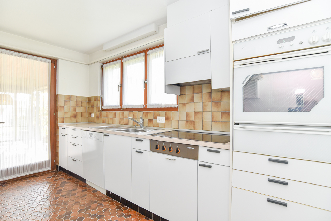 Helle Küche mit Holzfenstern und Fliesenboden