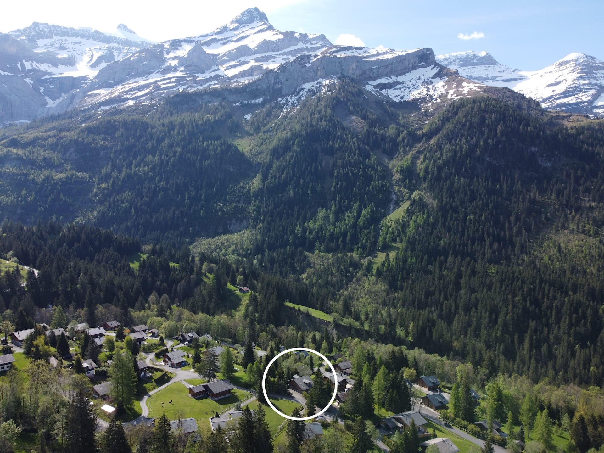 Luftaufnahme einer alpinen Bergsiedlung mit Schneegipfeln