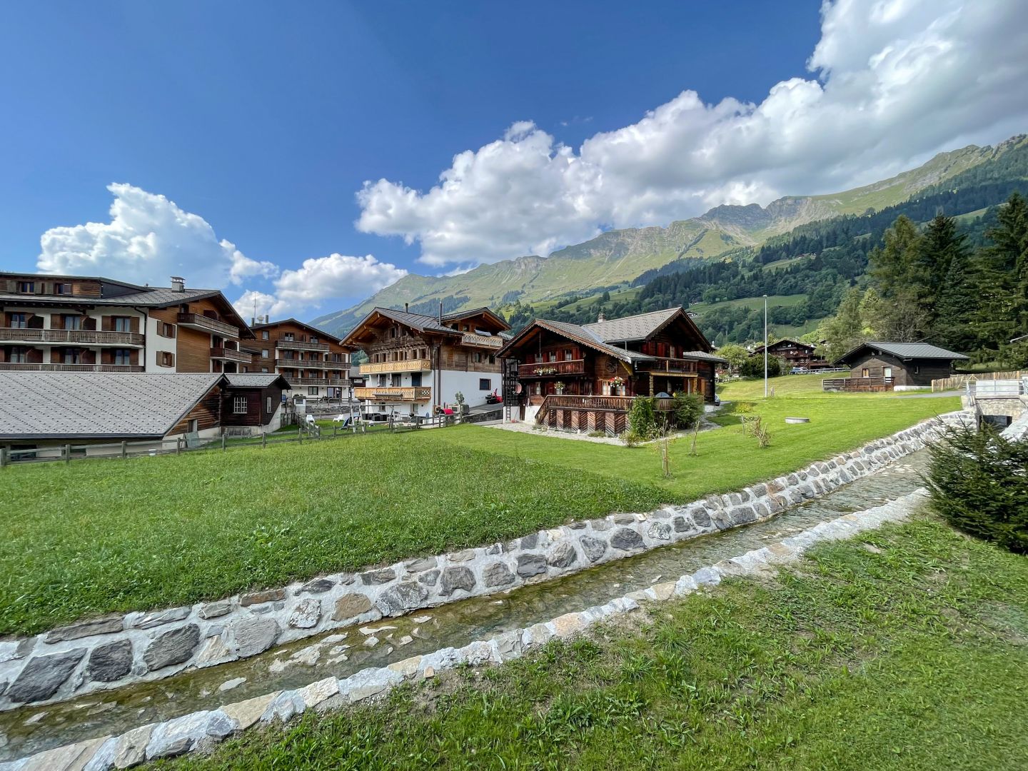 Alpines Dorf mit Wiesen und Bergpanorama