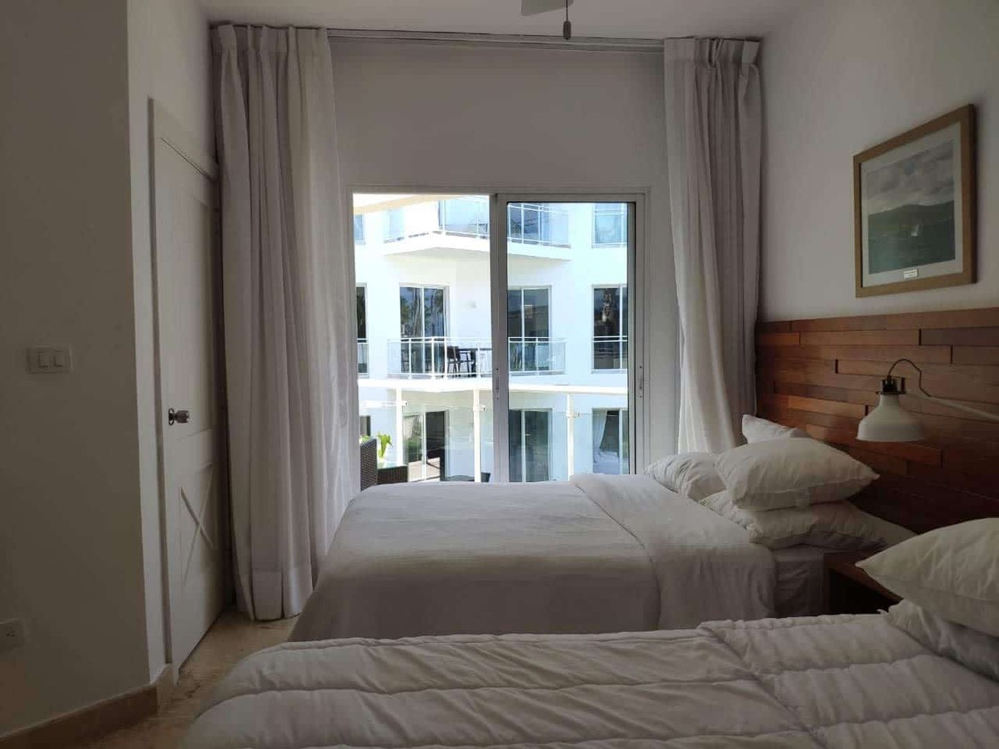 Helles Schlafzimmer mit Doppelbett und Balkonblick