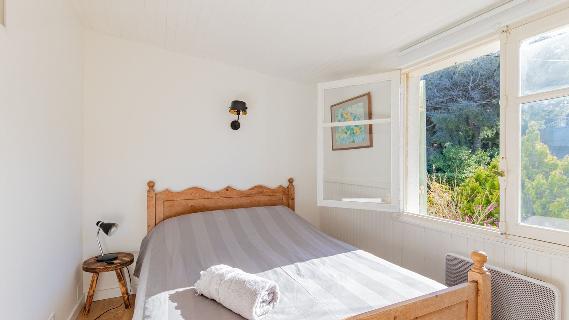 Helles Schlafzimmer mit offenem Fenster und Gartenblick