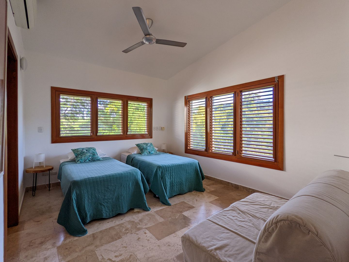 Schlafzimmer mit zwei Einzelbetten und großen Holzfenstern
